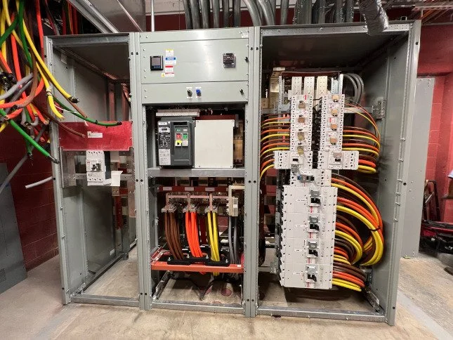 Electrical panel with circuit breakers and wiring in an industrial setting.