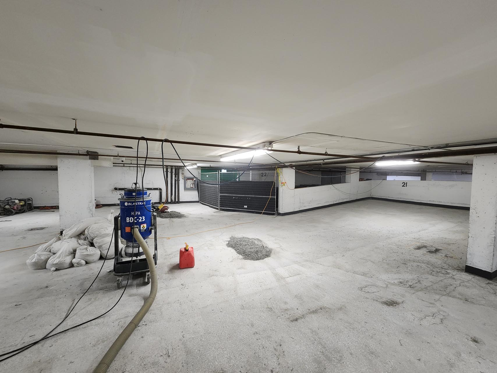 Underground parking garage under construction with cement floors, construction equipment, and wiring.