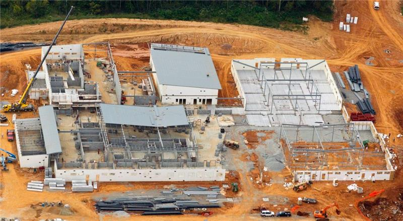 An aerial view of a construction site showing multiple building foundations and structures in progress with construction equipment and materials around.