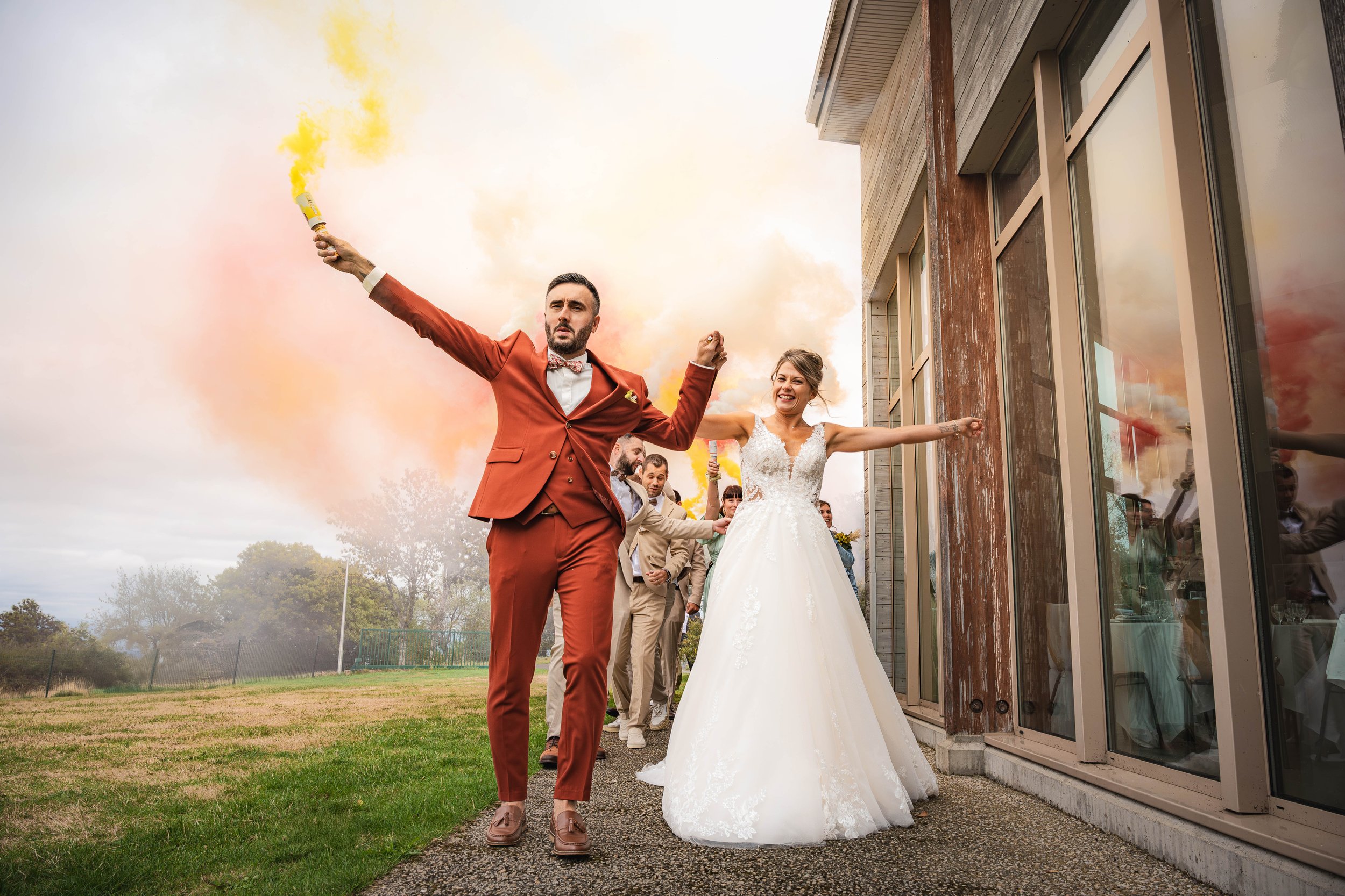 Mariés avec des fumigènes colorés devant le lieu de réception