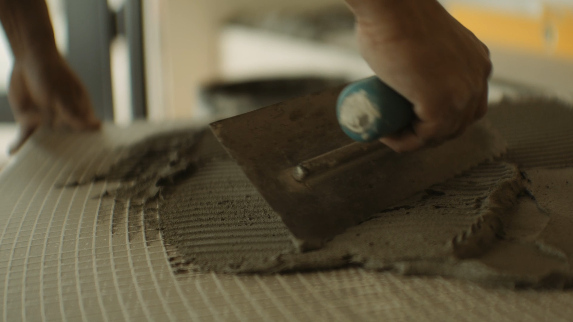 Close-up of a person smoothing wet cement with a trowel.