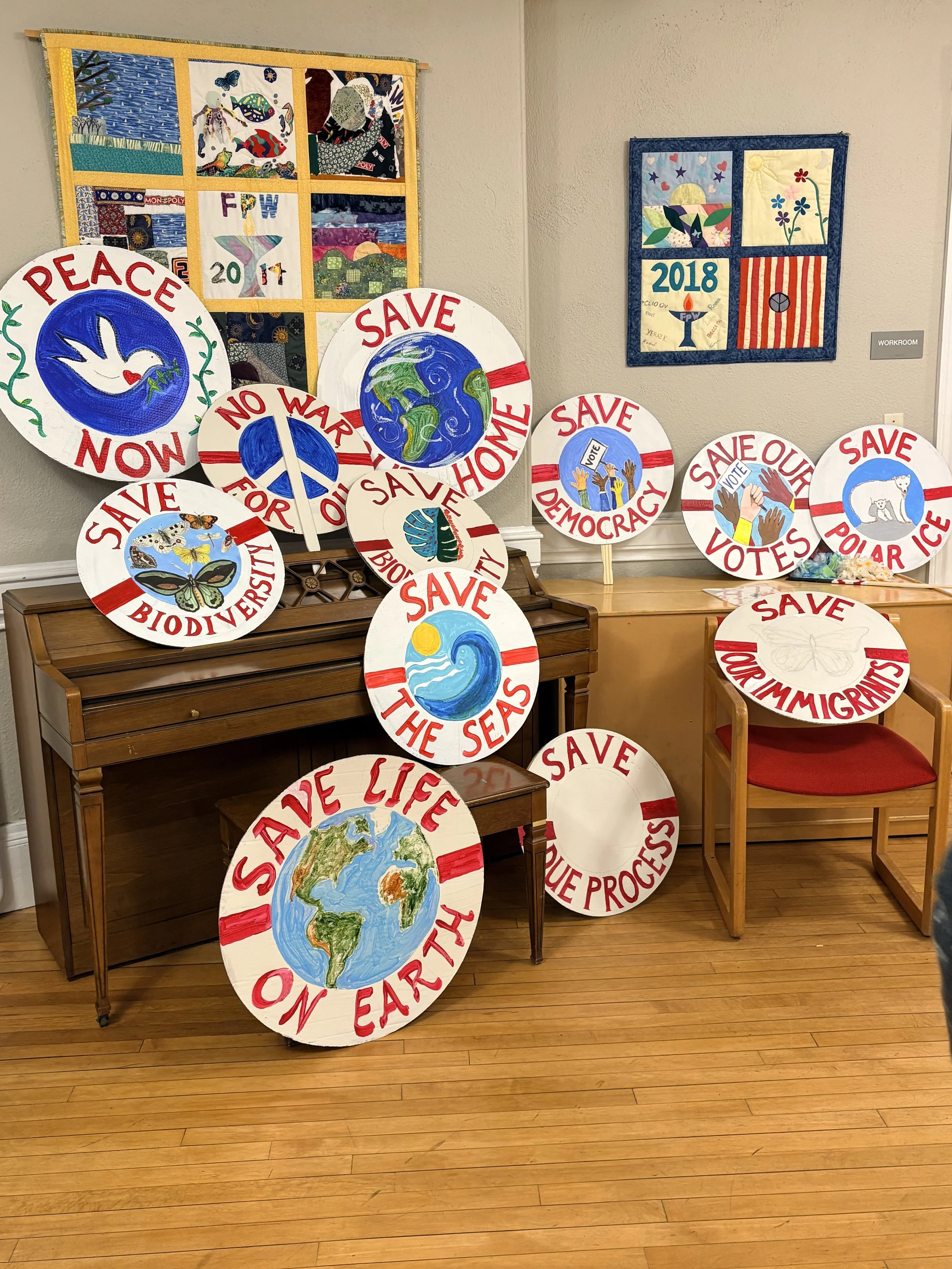 Display of handmade protest signs with slogans such as "PEACE NOW," "SAVE OUR EARTH," "NO WAR".
