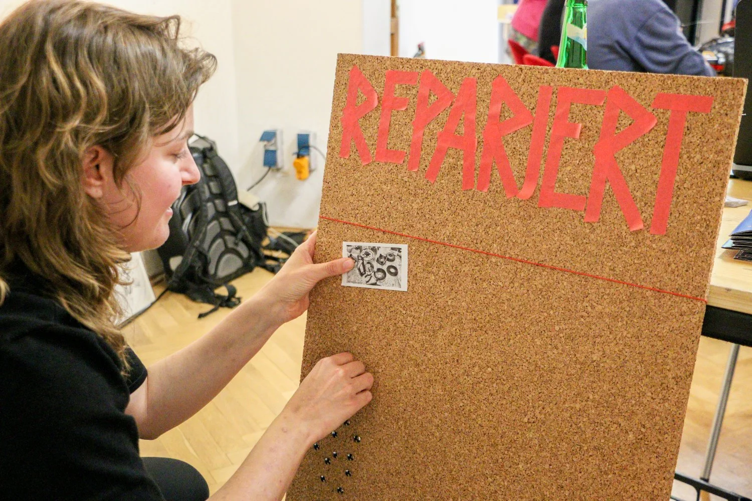 Person pinning photo to corkboard