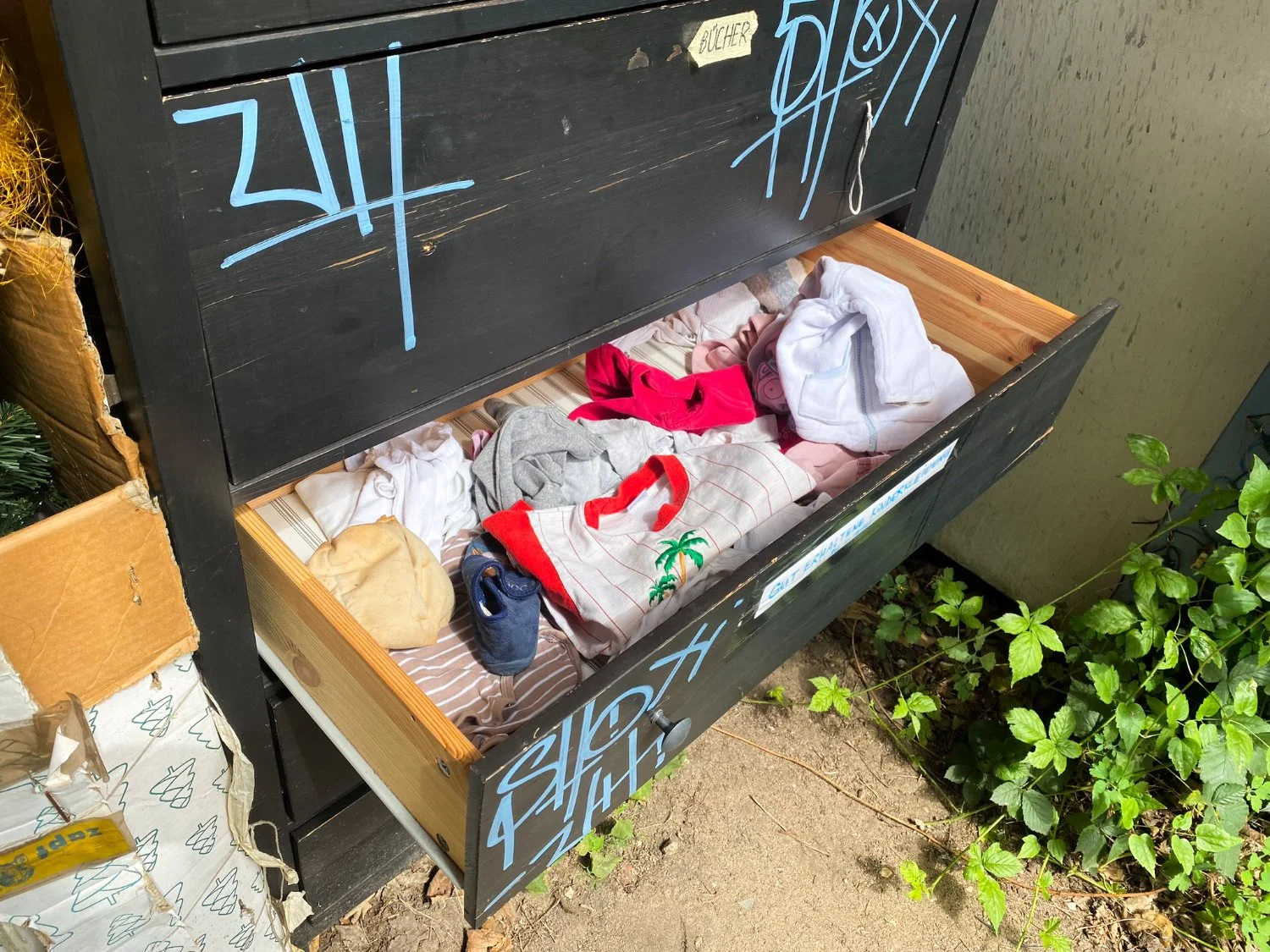 Sharing shelf with graffiti and a messy drawer that's been drawn out.