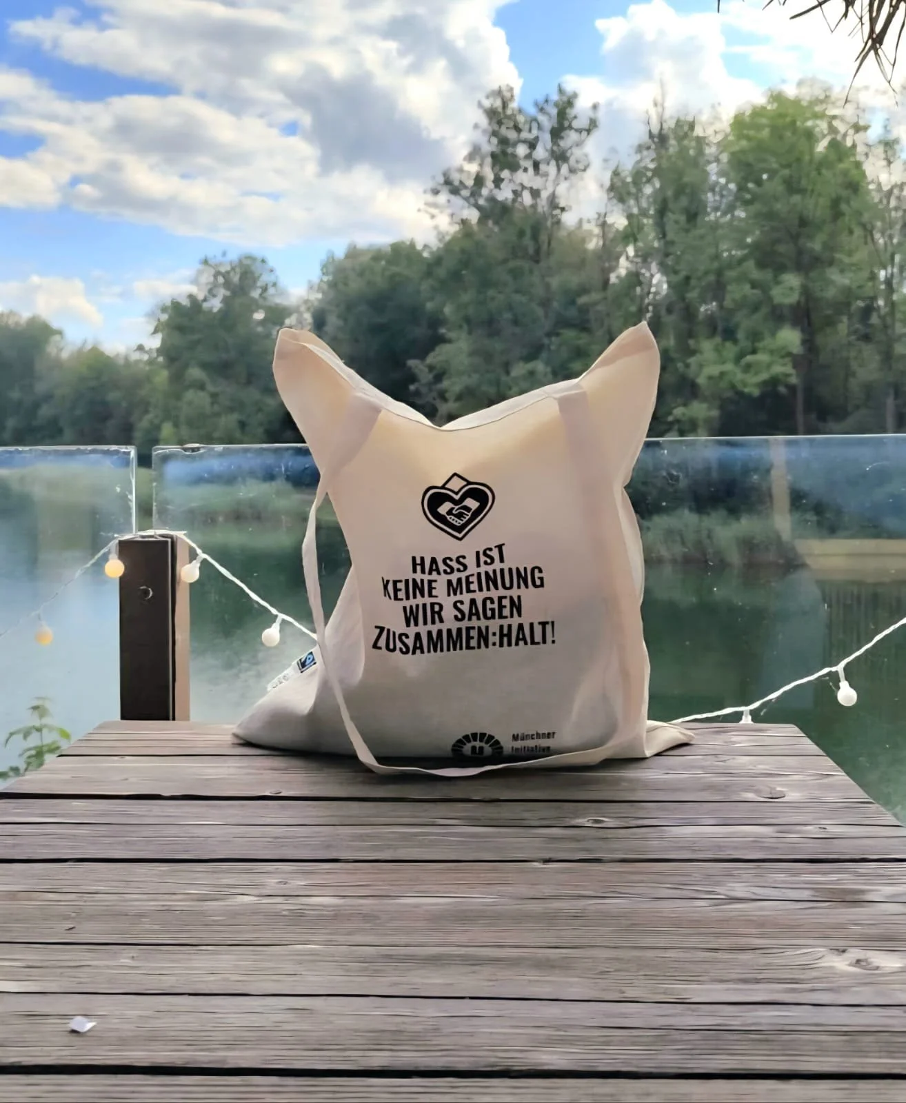 Foto von Stoffbeutel mit einem print. Der beutel liegt auf einen Tish und hat einen Natur Hintergrund am See