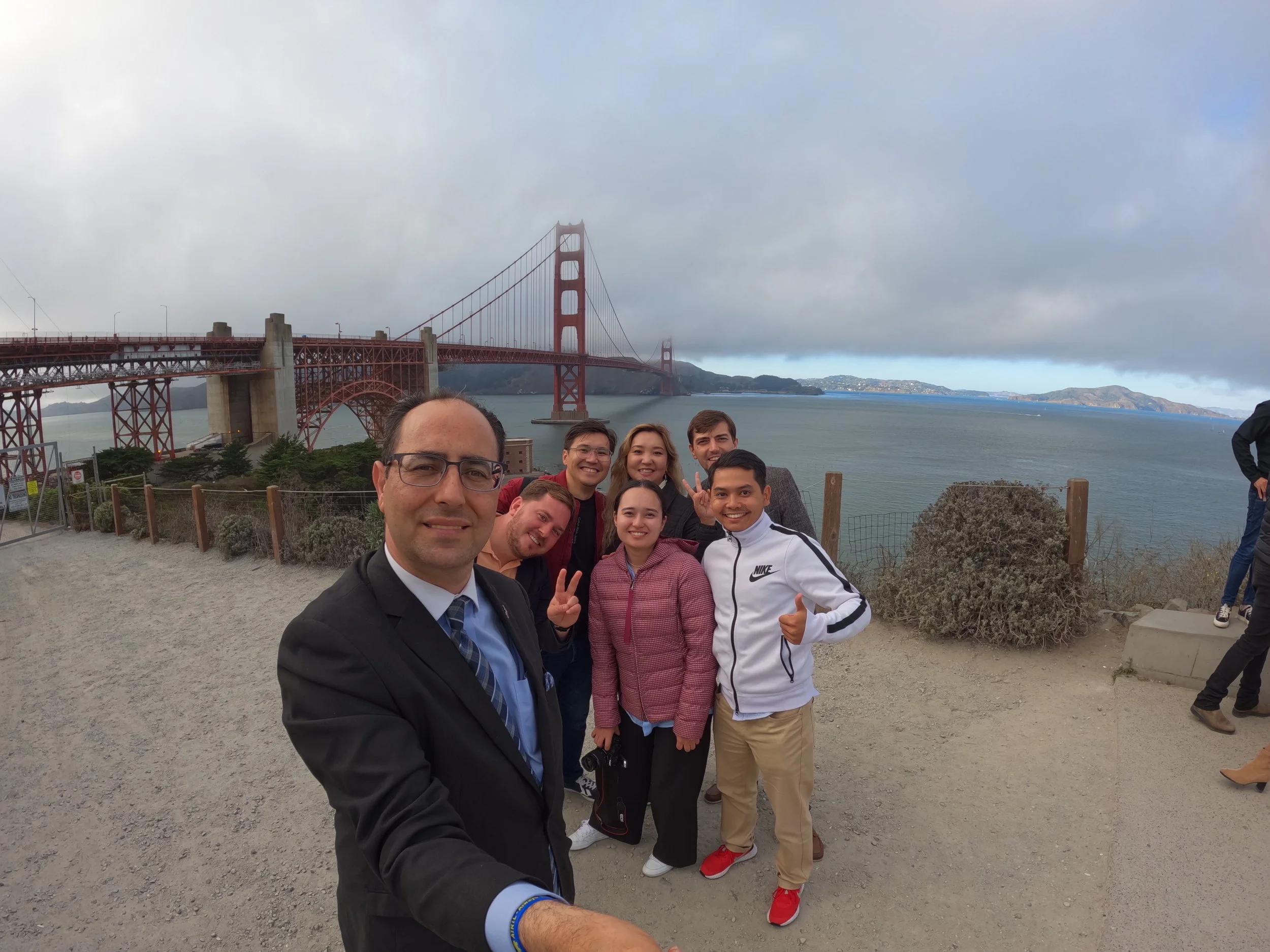 Group of seven people taking a selfie with the Golden Gate Bridge in the background.