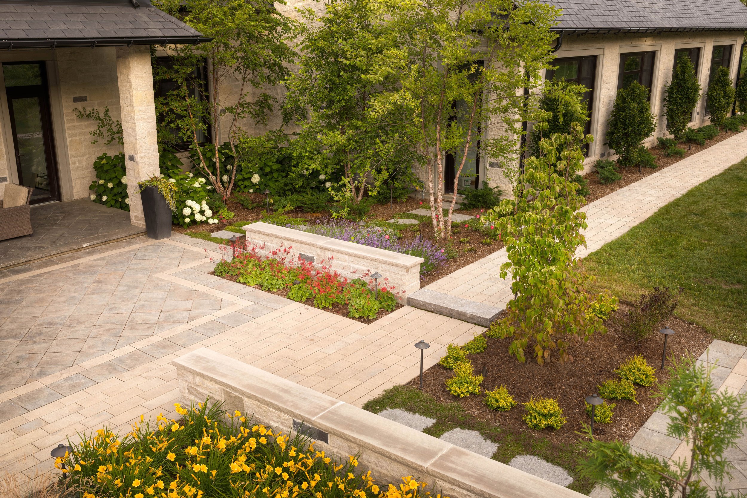 This side entrance leading to the indoor pool is it's own little oasis with birch trees, hydrangeas and a mix of seasonal perennials. Here we mixed both formal and informal styles of gardens which complements each other well. 