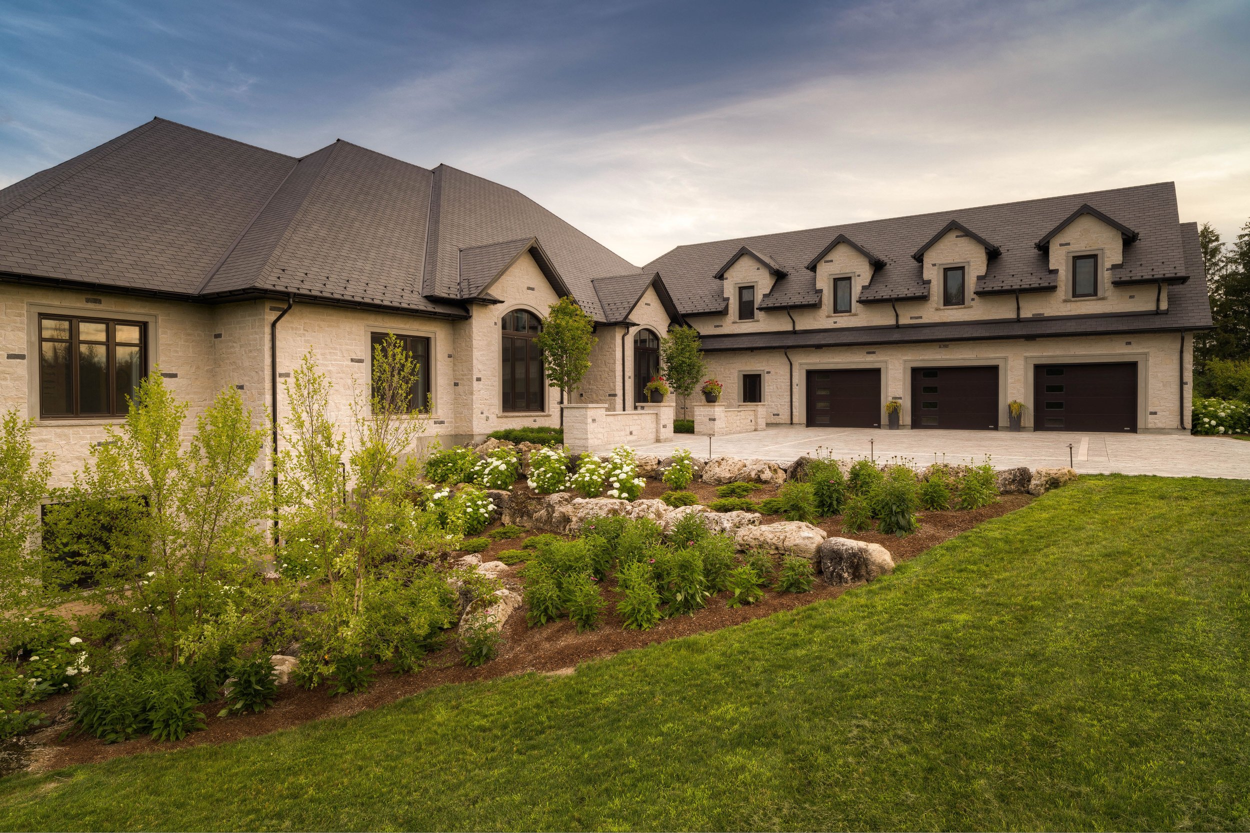 This informal style garden off the front entrance of the home features more birch with a mix of echinacea and hydrangea. The natural limestone boulders create a natural layering effect. 