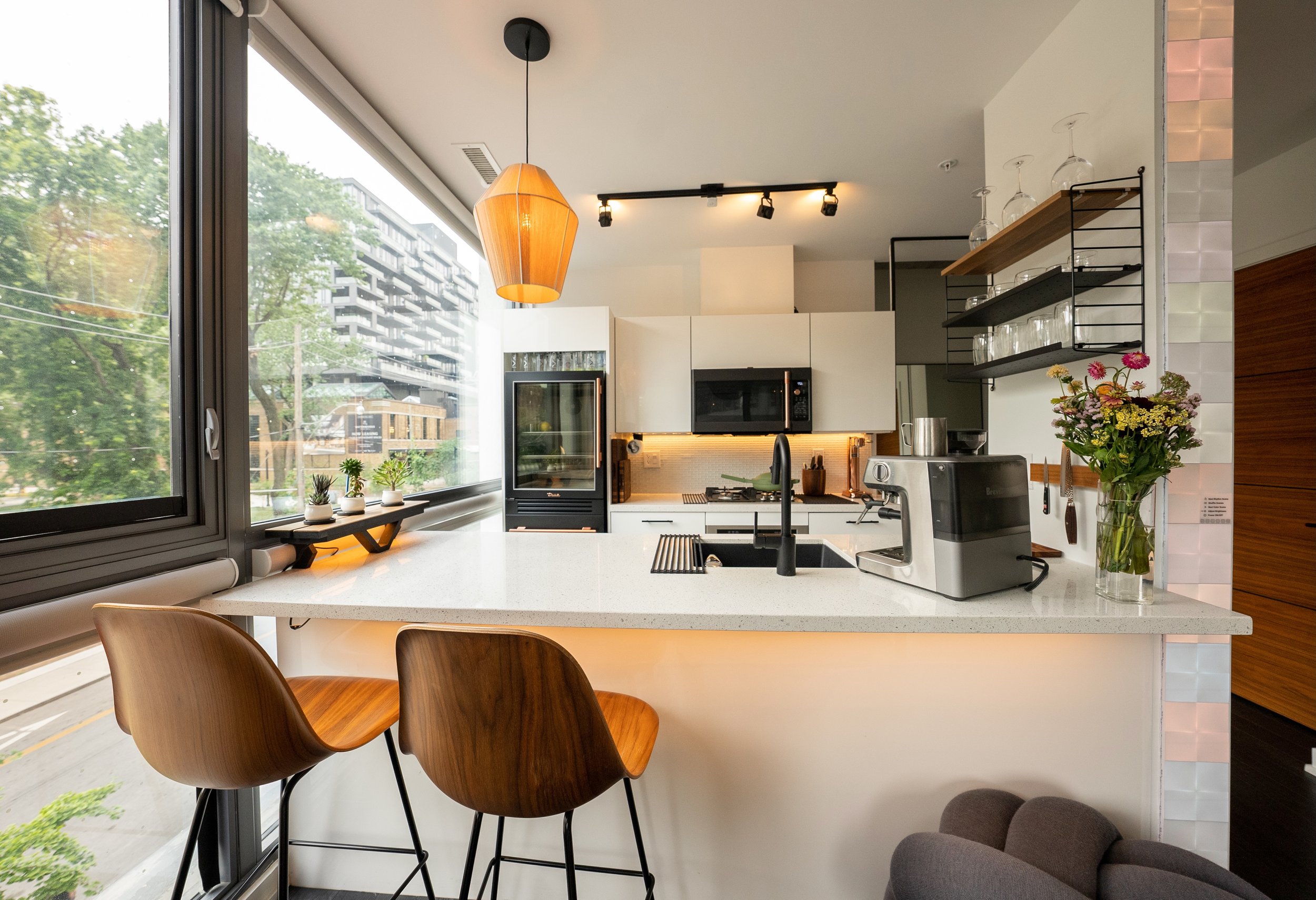 This open concept chef's table at the island allows for eating regular meals but also entertaining while cooking. Mixed lighting makes for a great nighttime ambience. The glass door fridge adds an element of luxury and surprise. 