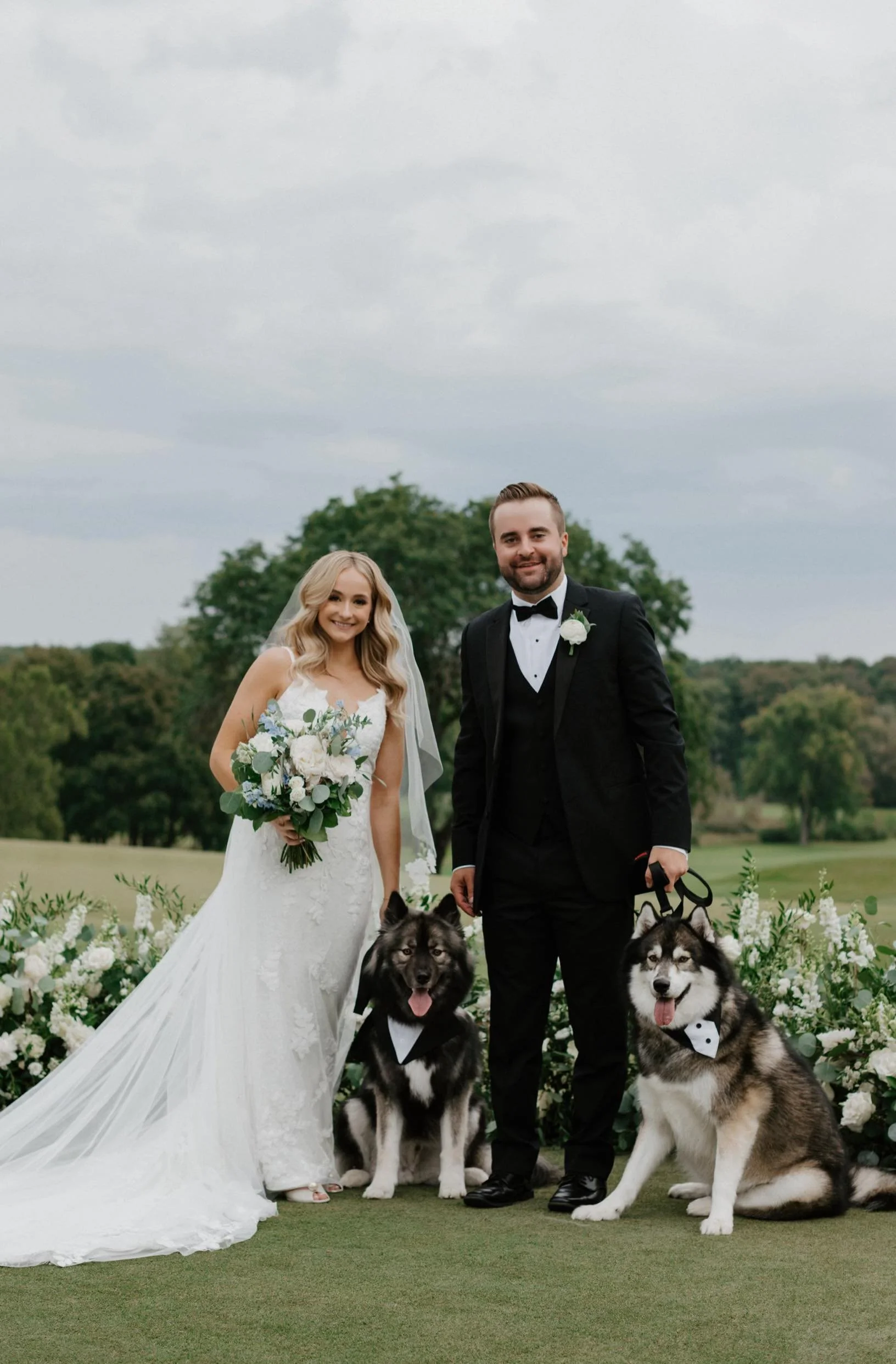 Dog in wedding attire posing with bride and groom.