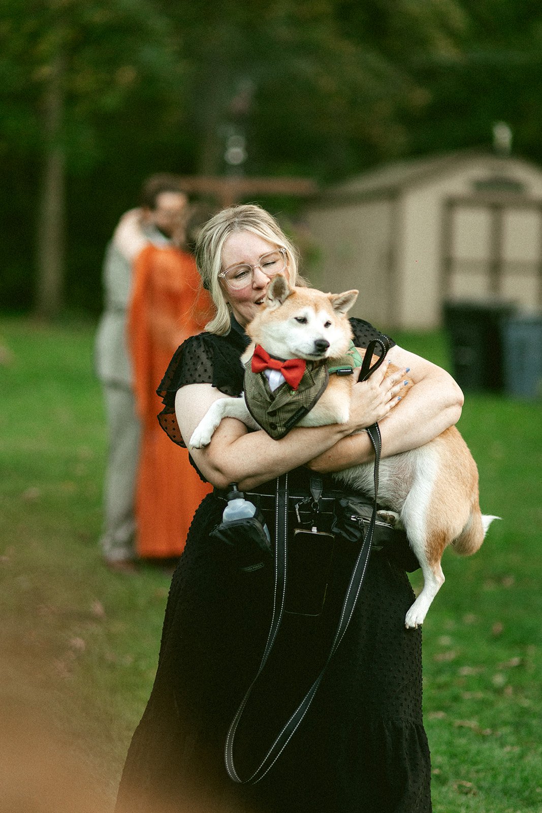 Happy dog wedding attendant carrying pup down Chicago wedding aisle.
