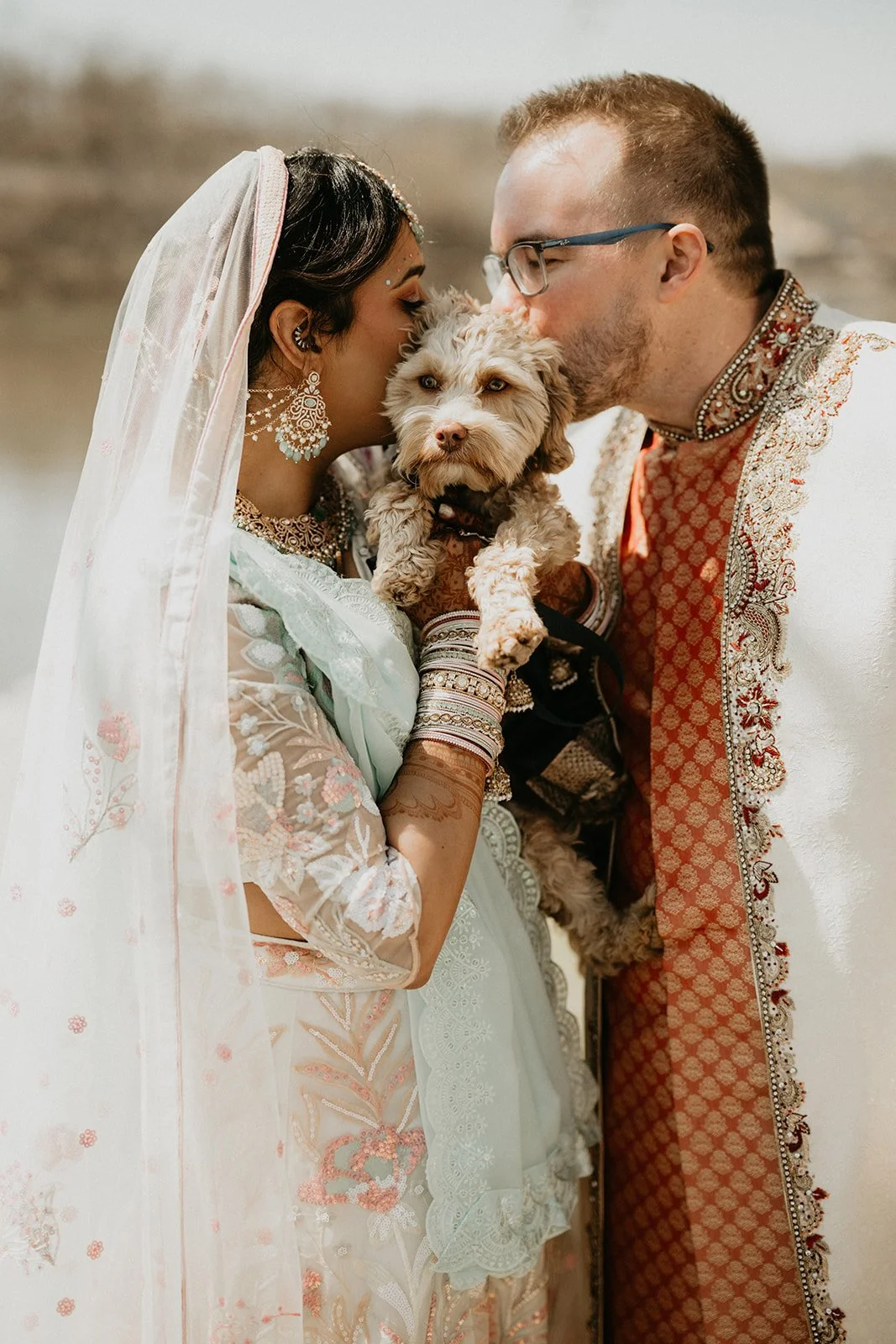 Bride and groom in traditional Indian wedding attire posing with their dog in Chicago.
