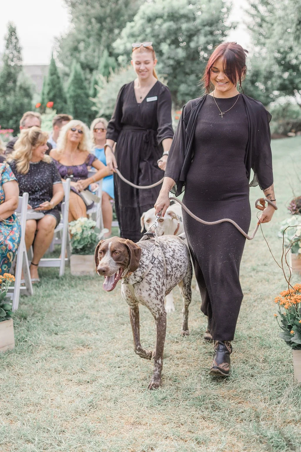 Professional dog wedding attendant team escorting dog during ceremony down the aisle. 