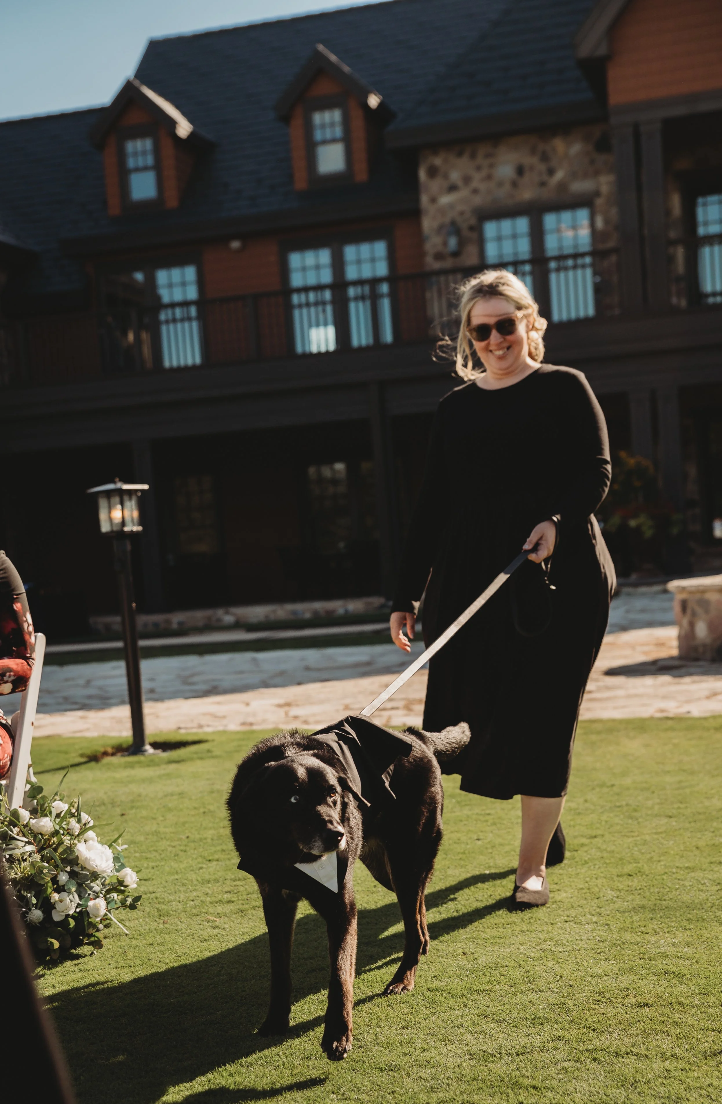 Dog in wedding attire being guided down the aisle by pet attendant for wedding at Beloit Club. 