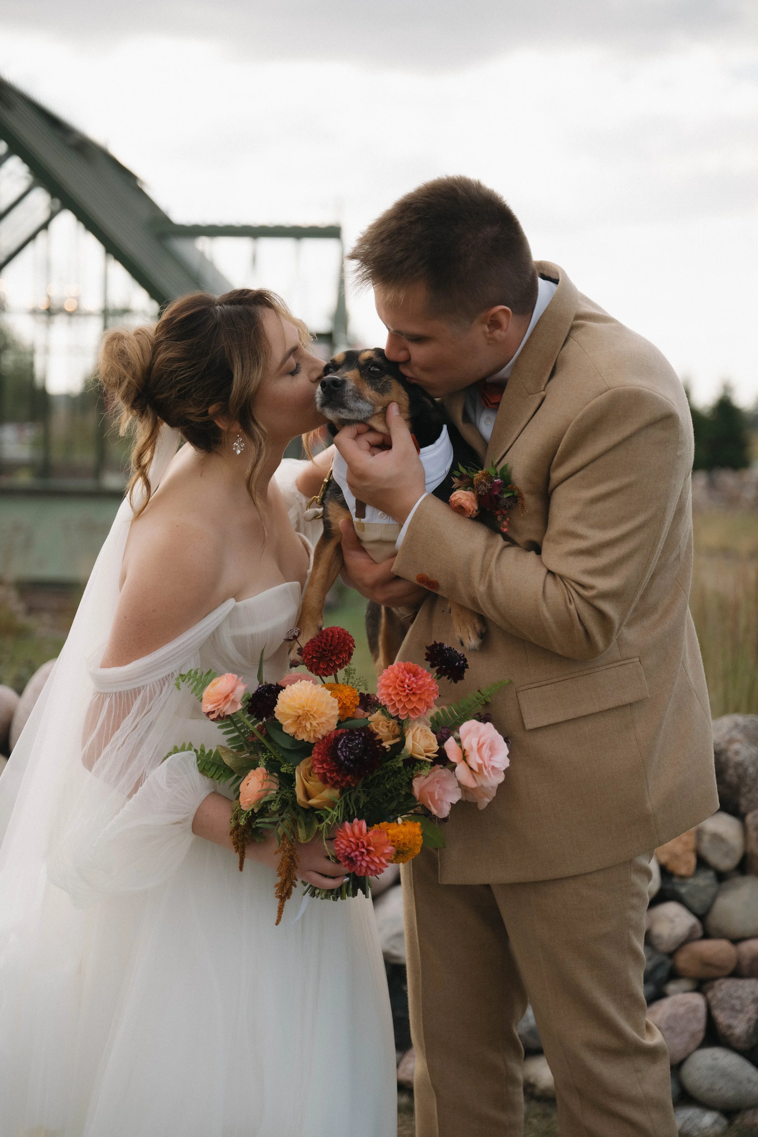 Bride and groom kissing their dog during Wisconsin wedding portraits with professional dog wedding attendant support.