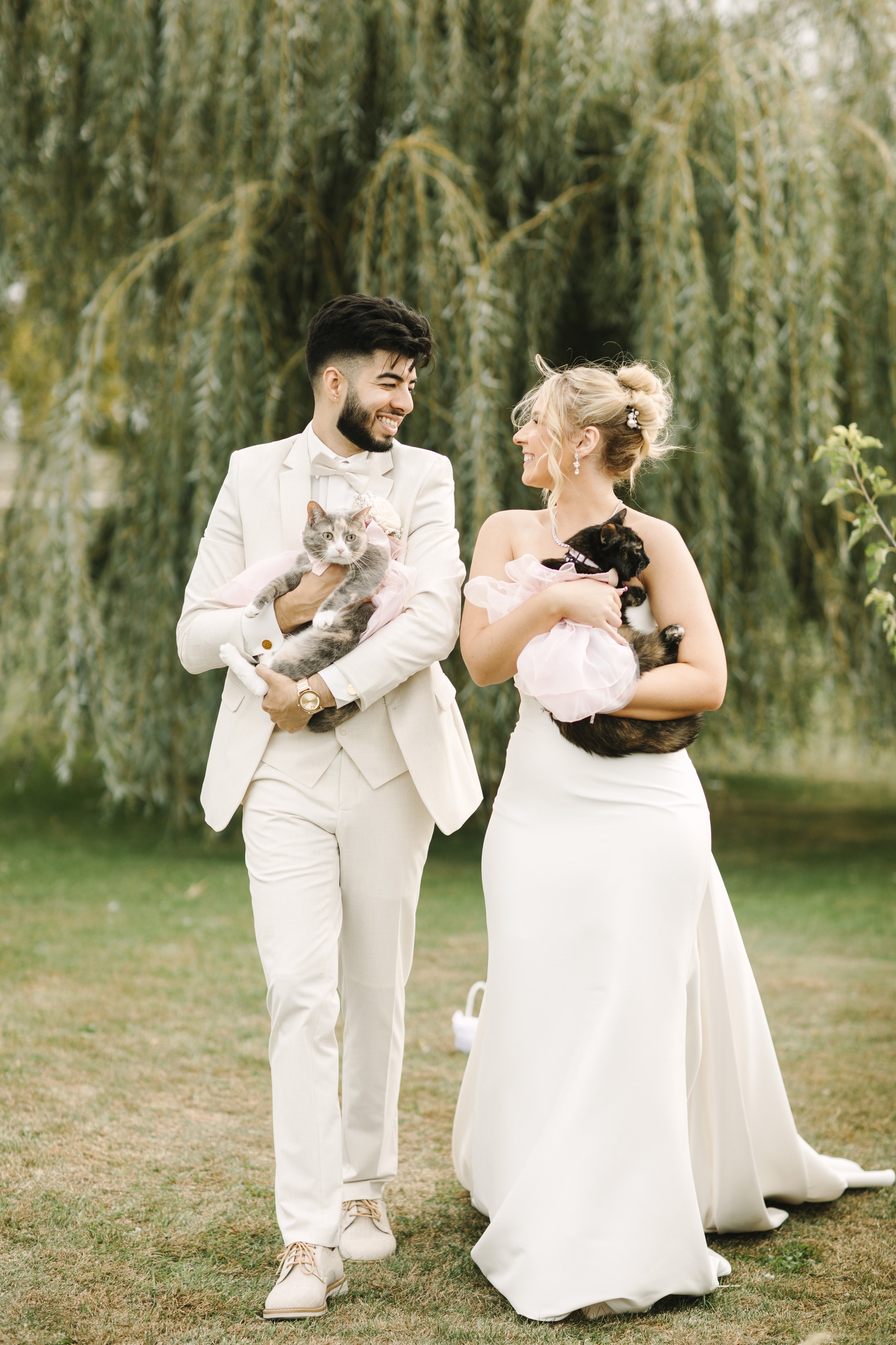 Couple posing with their cats in wedding attire during their wedding day. 