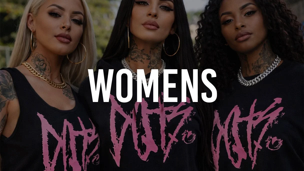 Three women with tattoos and jewelry standing outdoors, wearing black t-shirts with purple graffiti-style text that says "The Queens" and a large white overlay text that says "Womens".