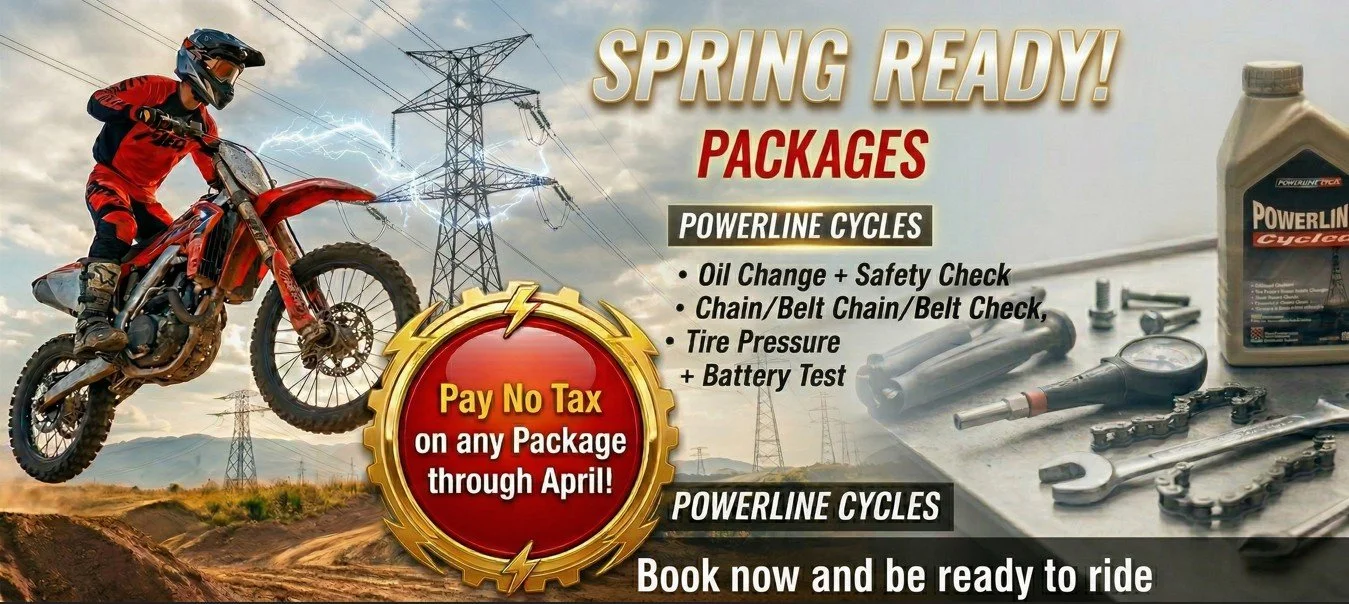 An advertisement for motorcycle servicing packages featuring a dirt bike rider in red gear performing a jump against a cloudy sky and electrical towers. It promotes spring-ready packages including oil change, safety check, chain check, tire pressure, and battery test, with a special offer to pay no tax on packages through April. The background includes motorcycle tools and a bottle of oil.