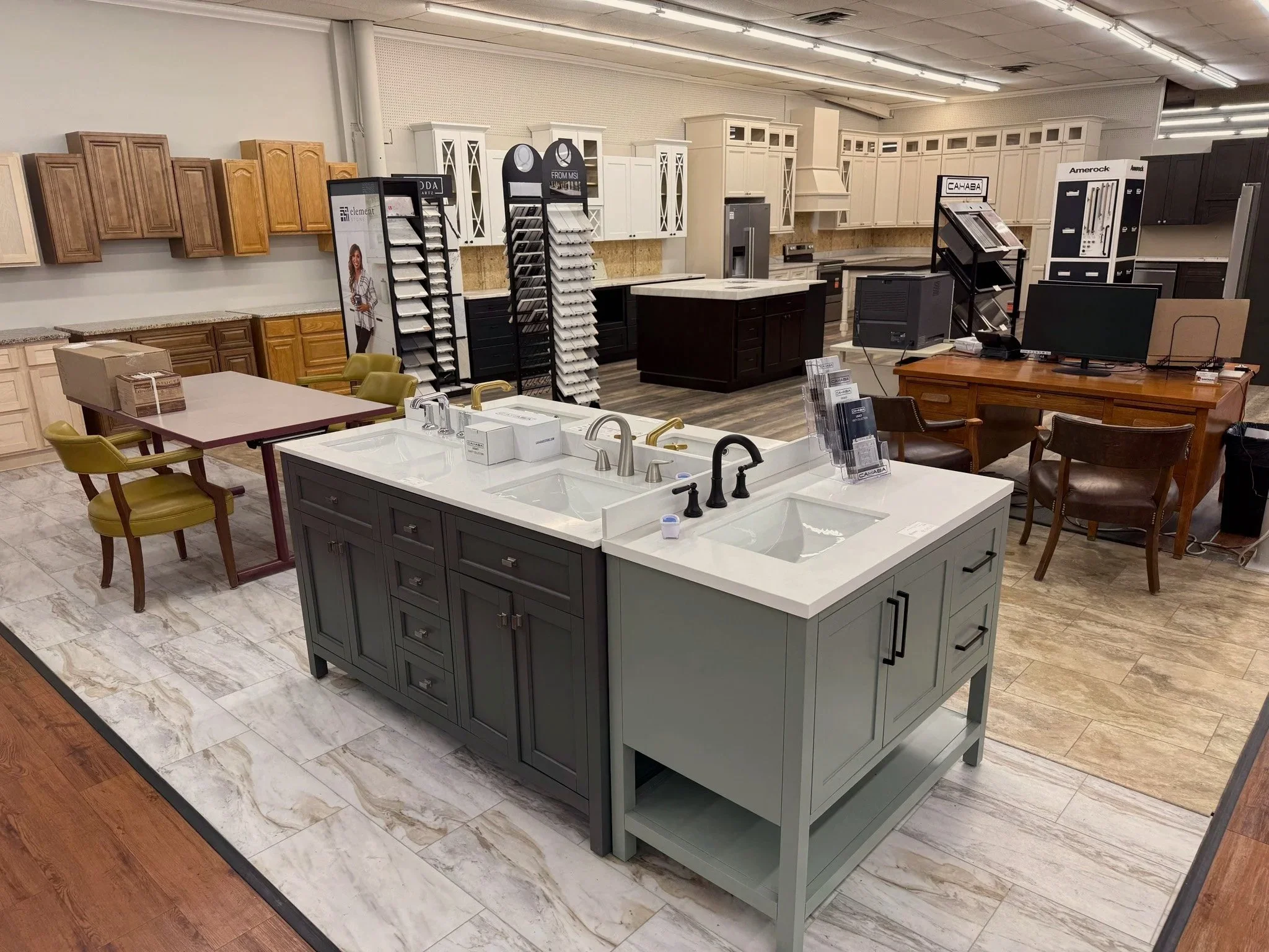 Interior of a kitchen showroom displaying various cabinet and countertop styles, with a kitchen island in the foreground.