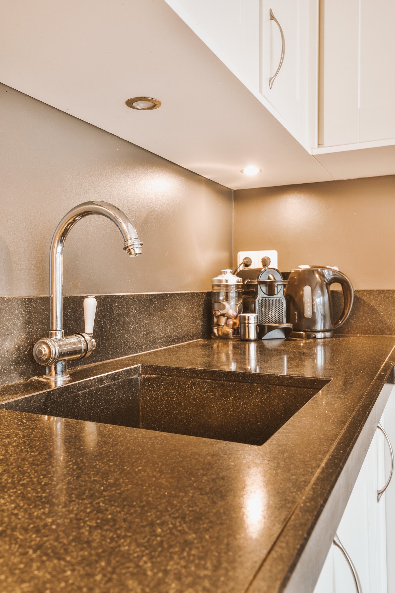 Kitchen counter with sink, faucet, coffee maker, and electric kettle.