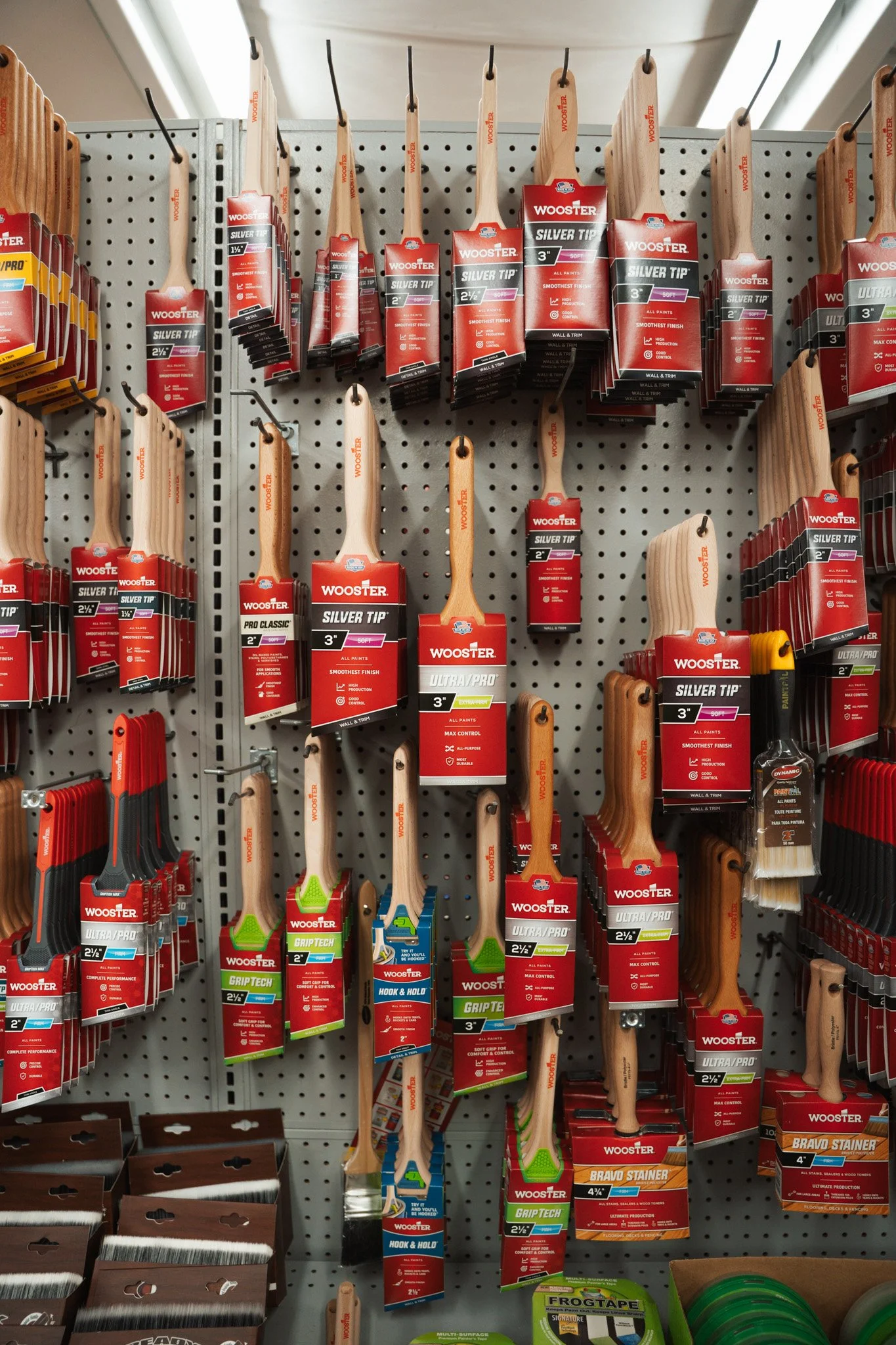 A display of various paintbrushes and painting tools hanging on a pegboard in a hardware store.