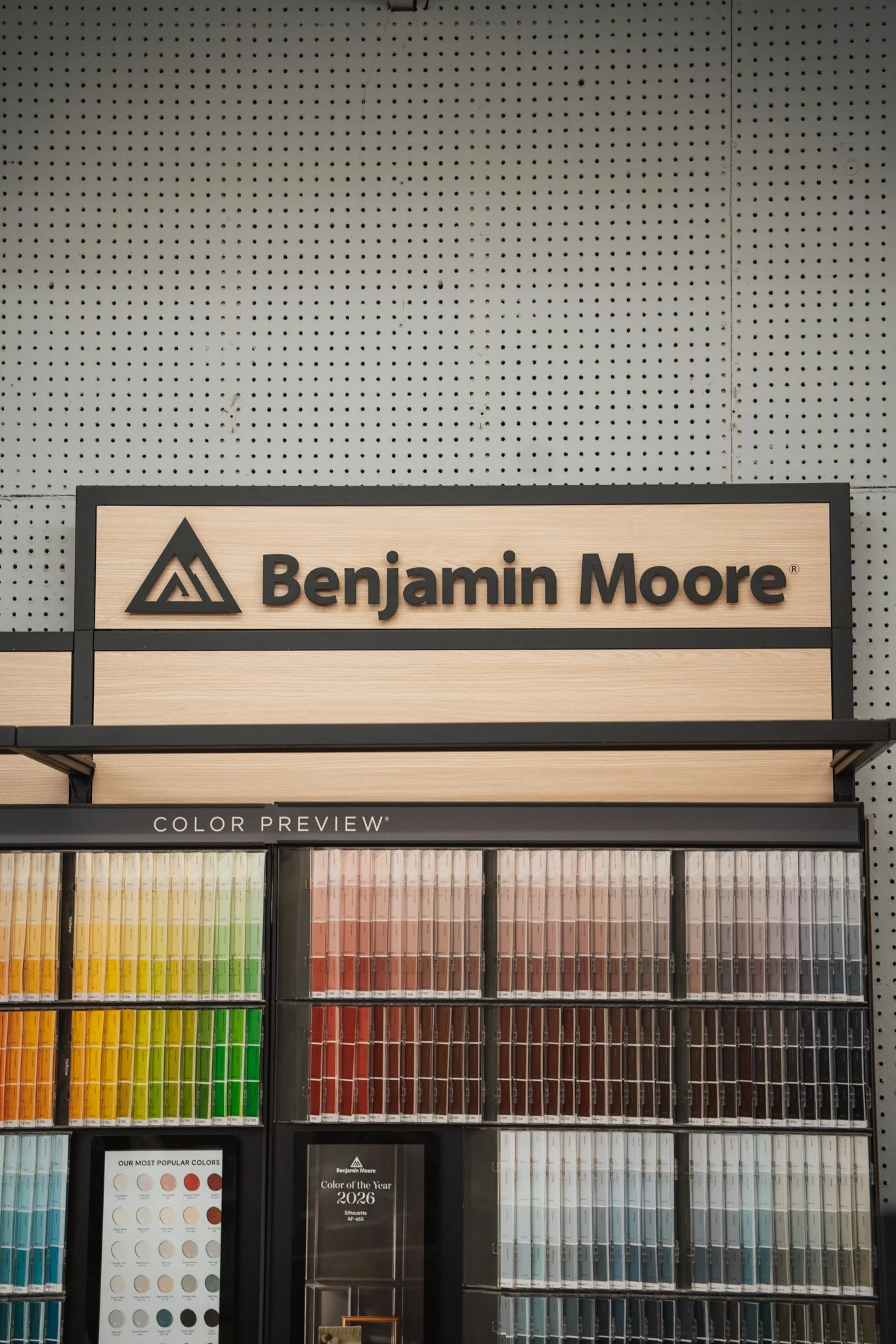 Benjamin Moore paint display with color samples arranged in rows and columns, featuring a sign that reads 'Color Preview' and a label indicating 'Color of the year 2026'.