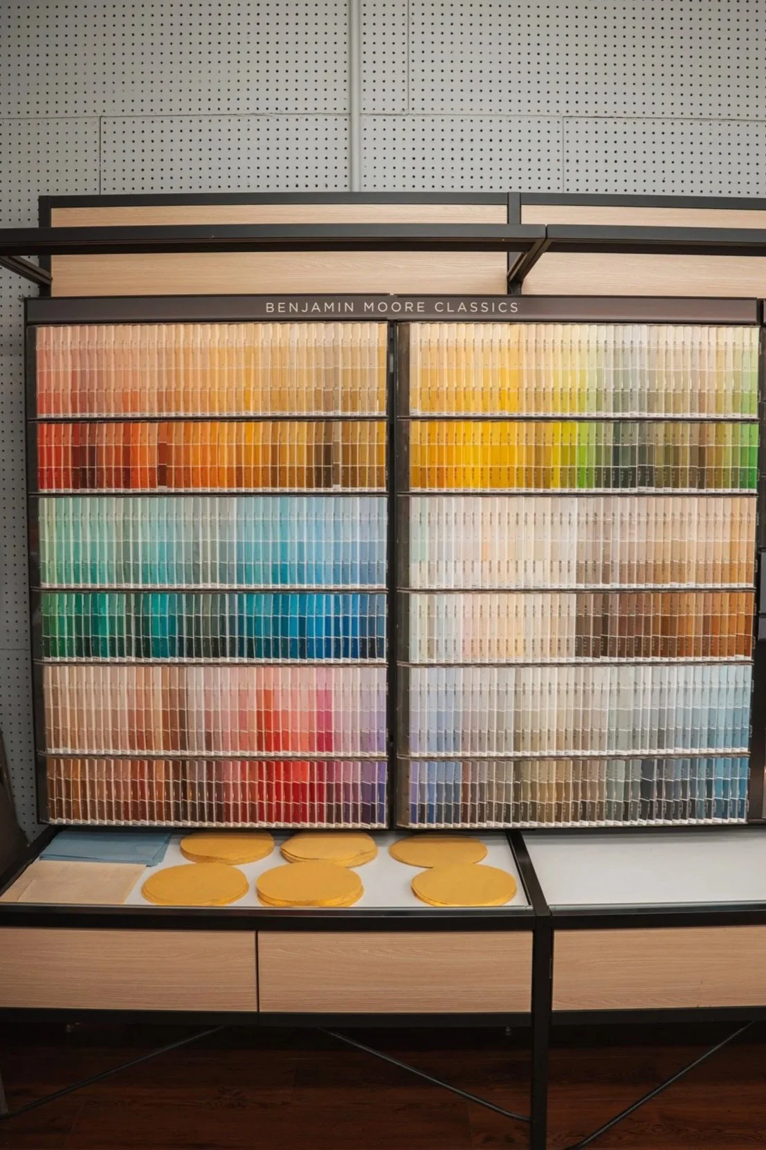 Color paint swatches organized by color on display rack, with labeled sections for Benjamin Moore Classics.