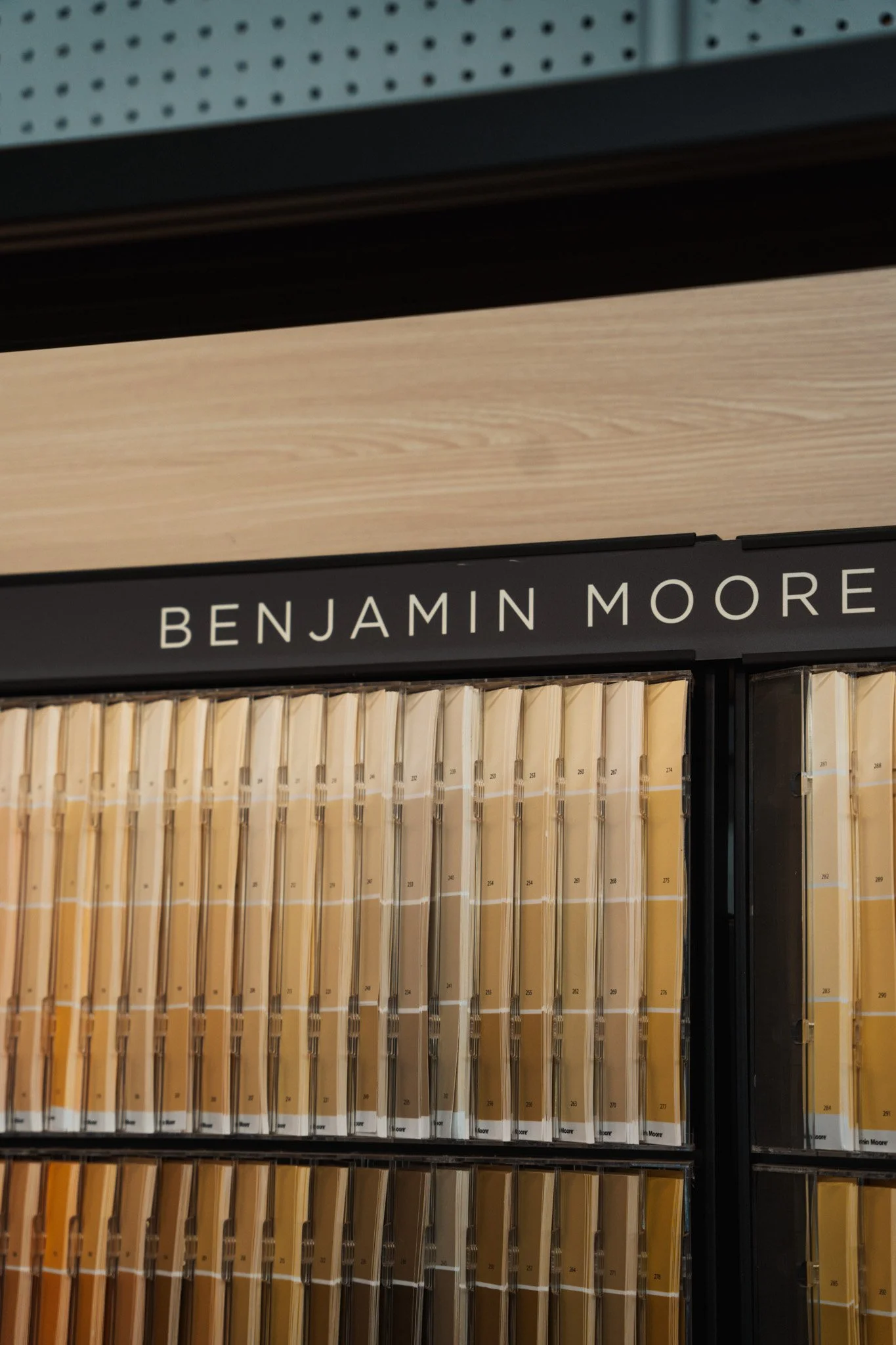 Close-up of a display shelf labeled 'Benjamin Moore' with various paint color samples.