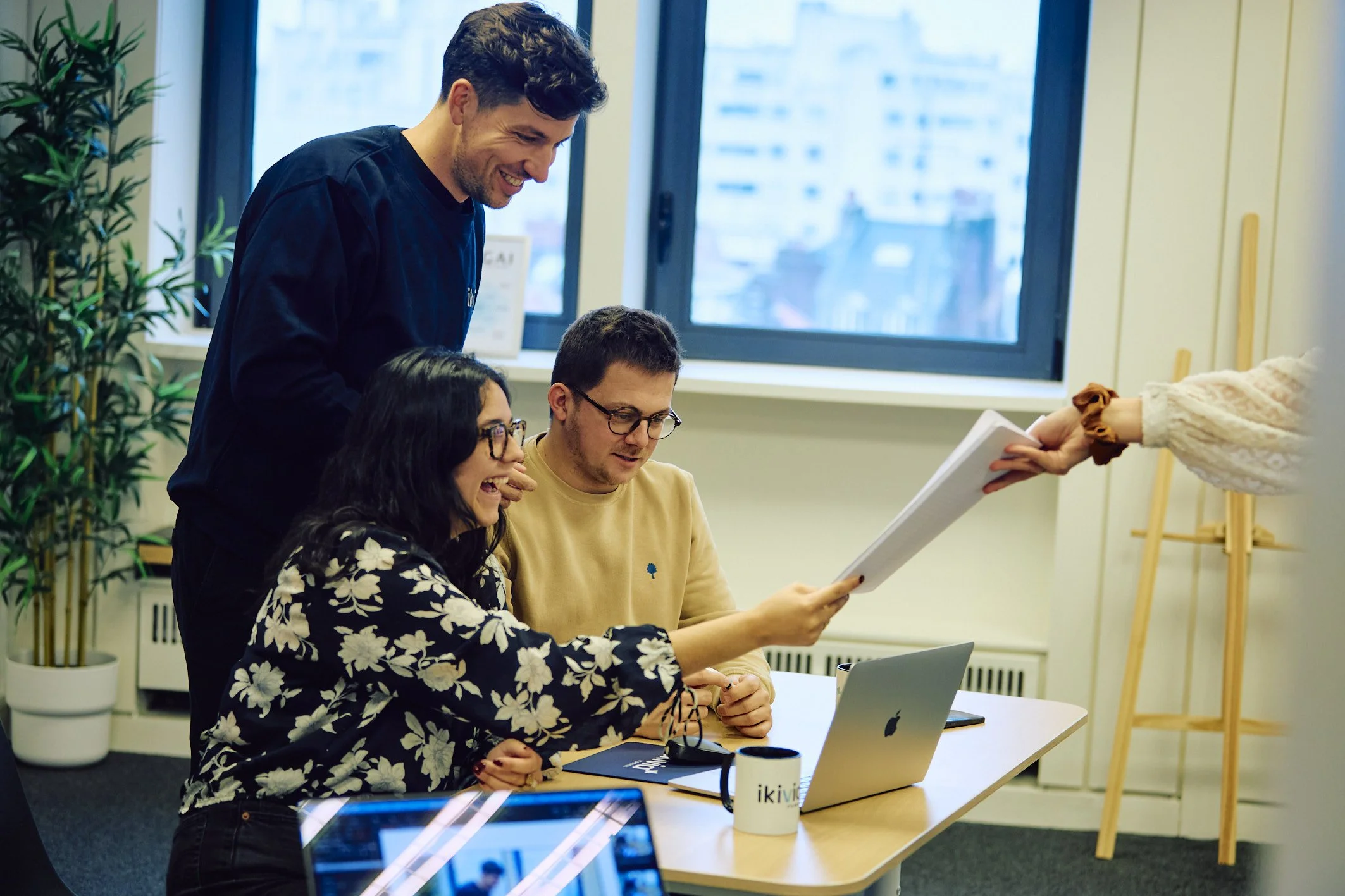 Trois collaborateurs sont en réunion et un autre leur dépose des documents.