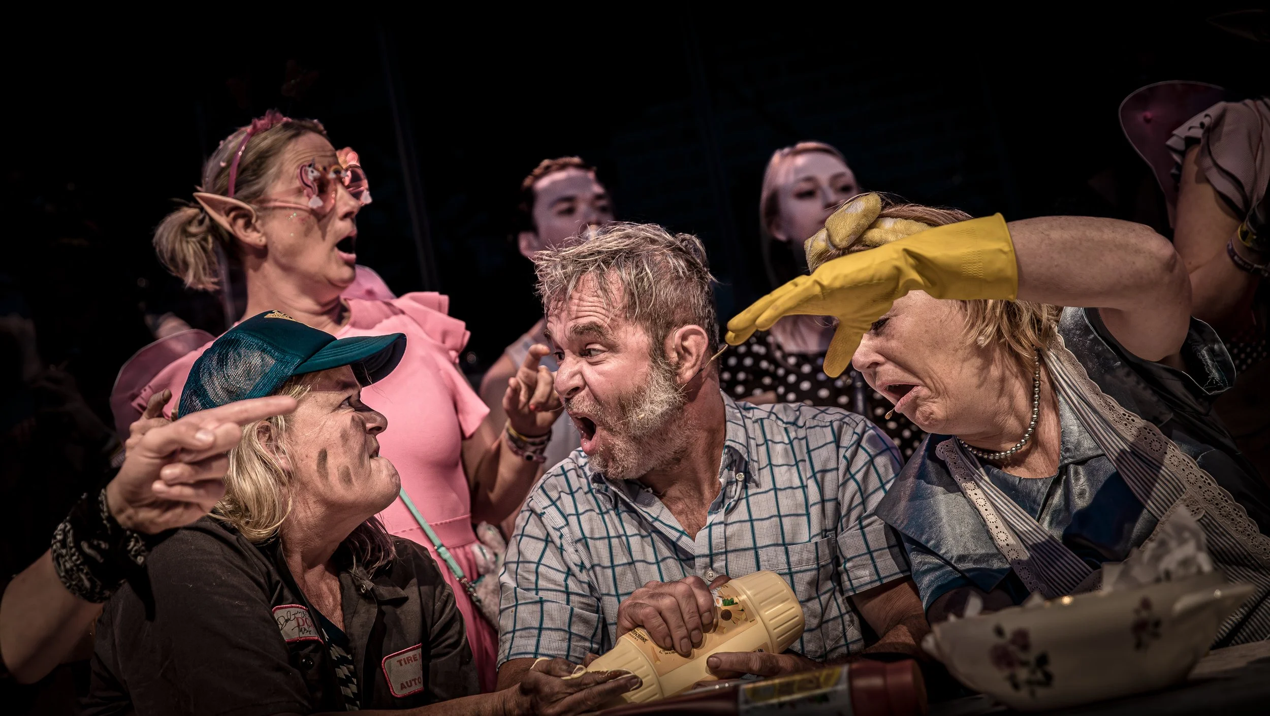 Diverse mensen in een discussie of ruzie, met uitgestrekte handen en boze gezichten, in een scène die lijkt op een confrontatie of conflict.