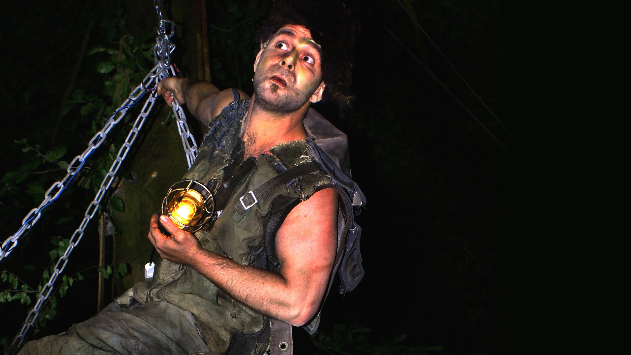 Man in het donker met een lamp en een stok