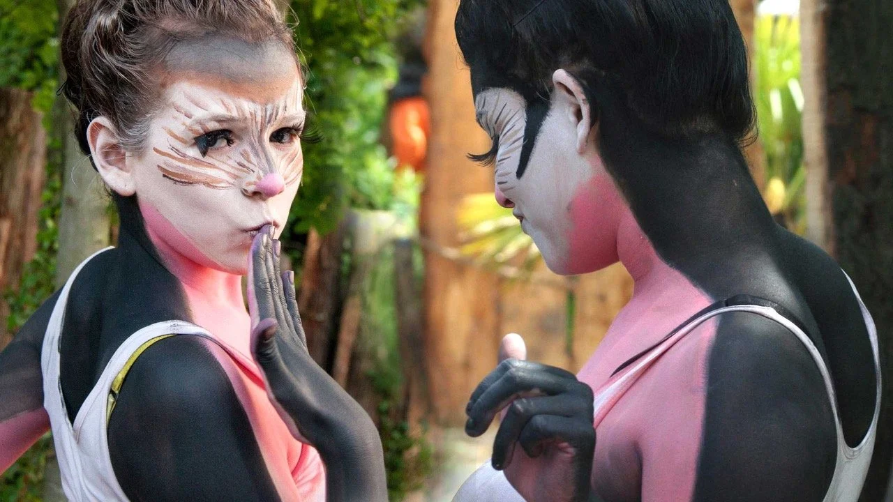 Twee mensen verkleed als egels met gezichtsmake-up en huidverf, op een groene buitenlocatie.