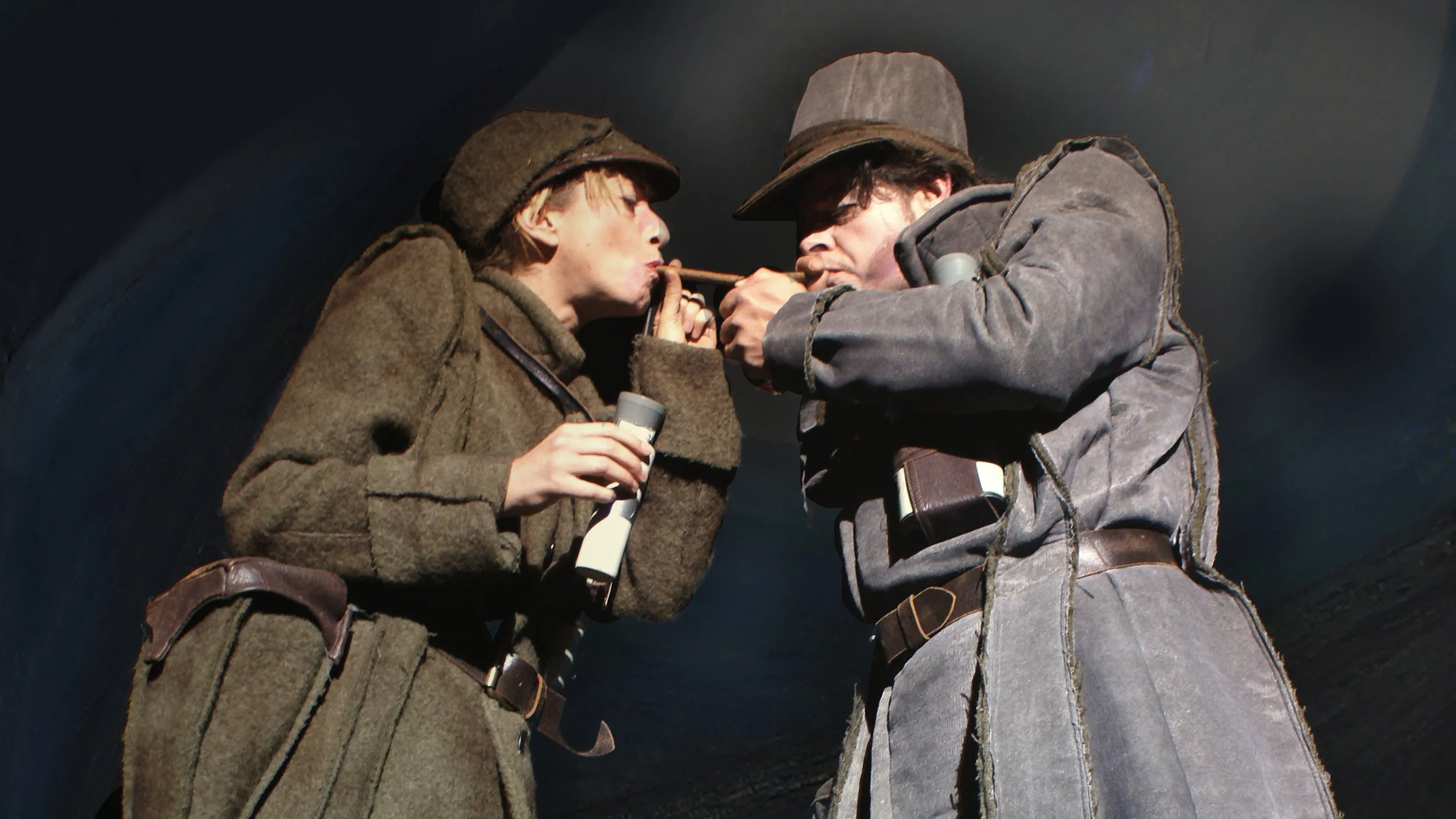 Twee personen gekleed in oude, ruwe uniformen kijken naar elkaar terwijl ze een sigaar tussen hun lippen vasthouden in een donkere setting.