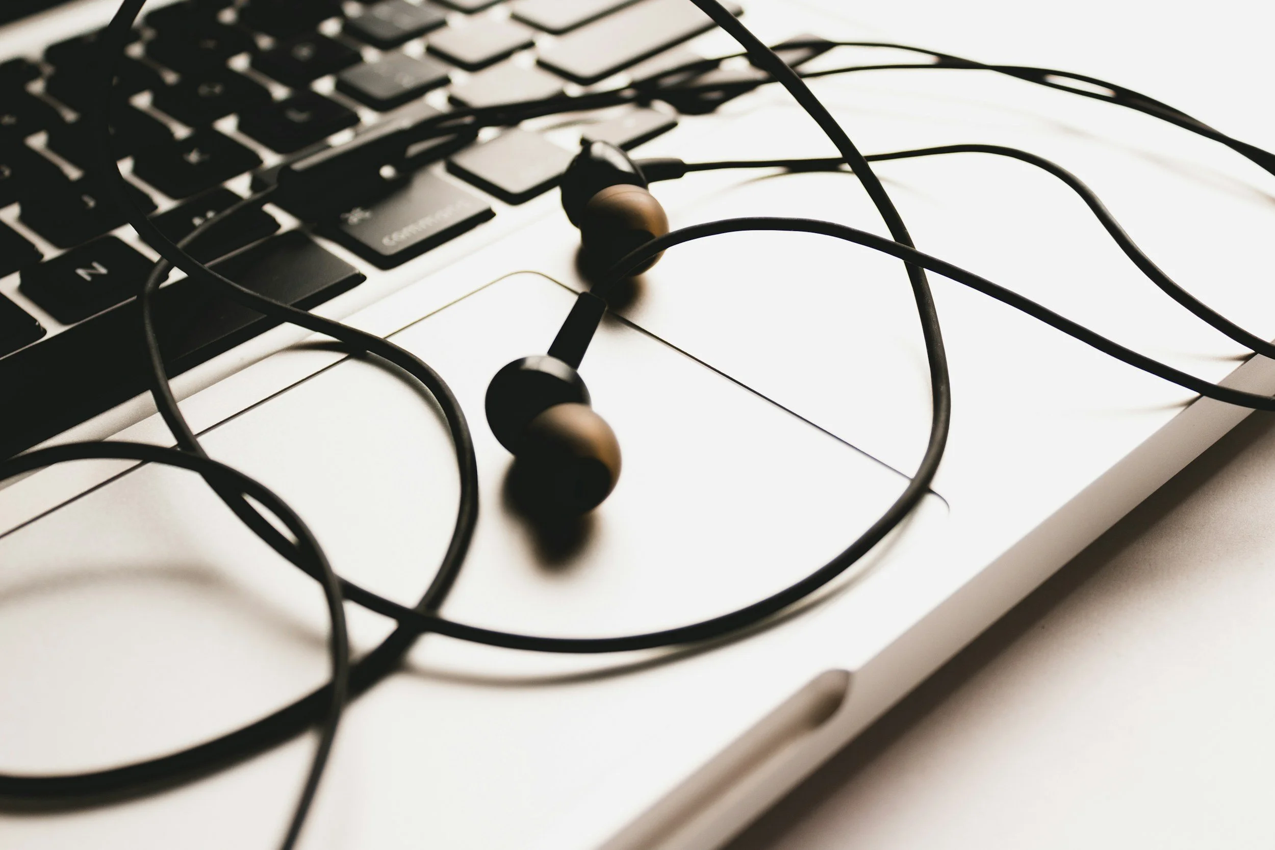 Earphones resting on a closed laptop keyboard and trackpad.