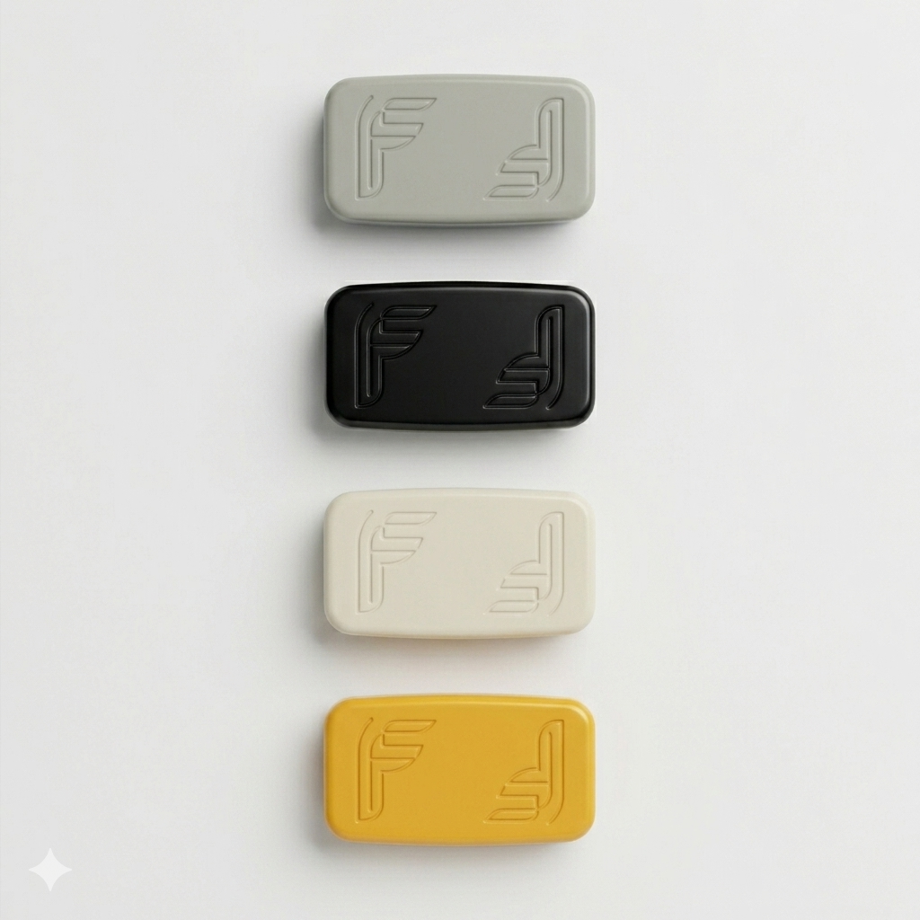 Four rectangular objects stacked vertically in different colors: gray, black, white, and yellow, each with embossed geometric lines and letter designs.