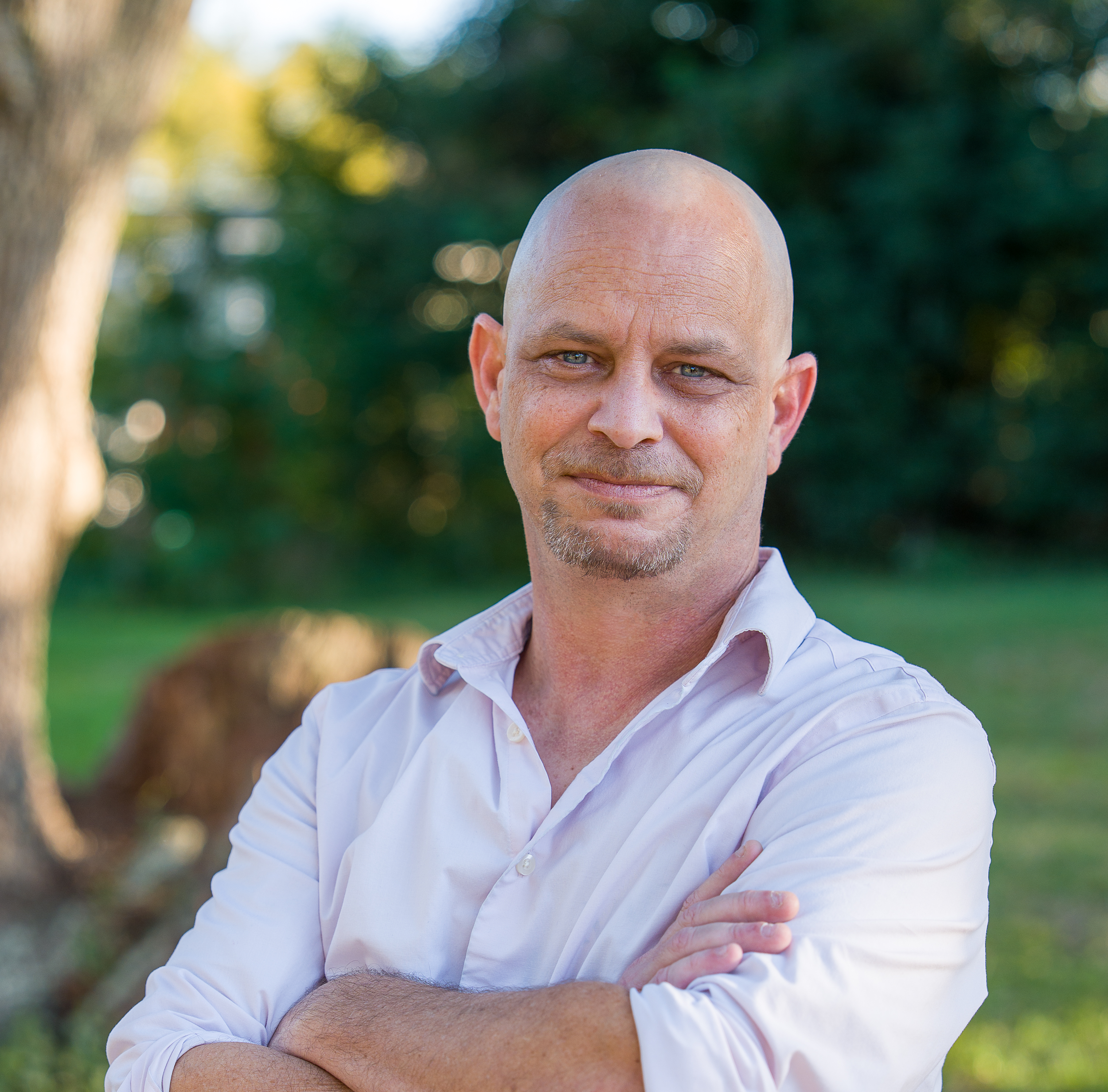 Close-up of a bald man wearing glasses and a black shirt taking a selfie indoors.