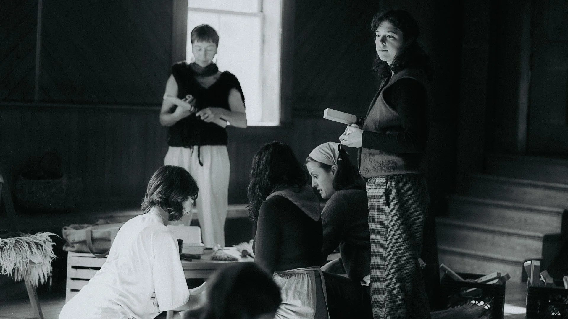 Groupe de personnes en réunion ou discussion dans une pièce à l'intérieur, avec un éclairage naturel venant d'une fenêtre ouverte.
