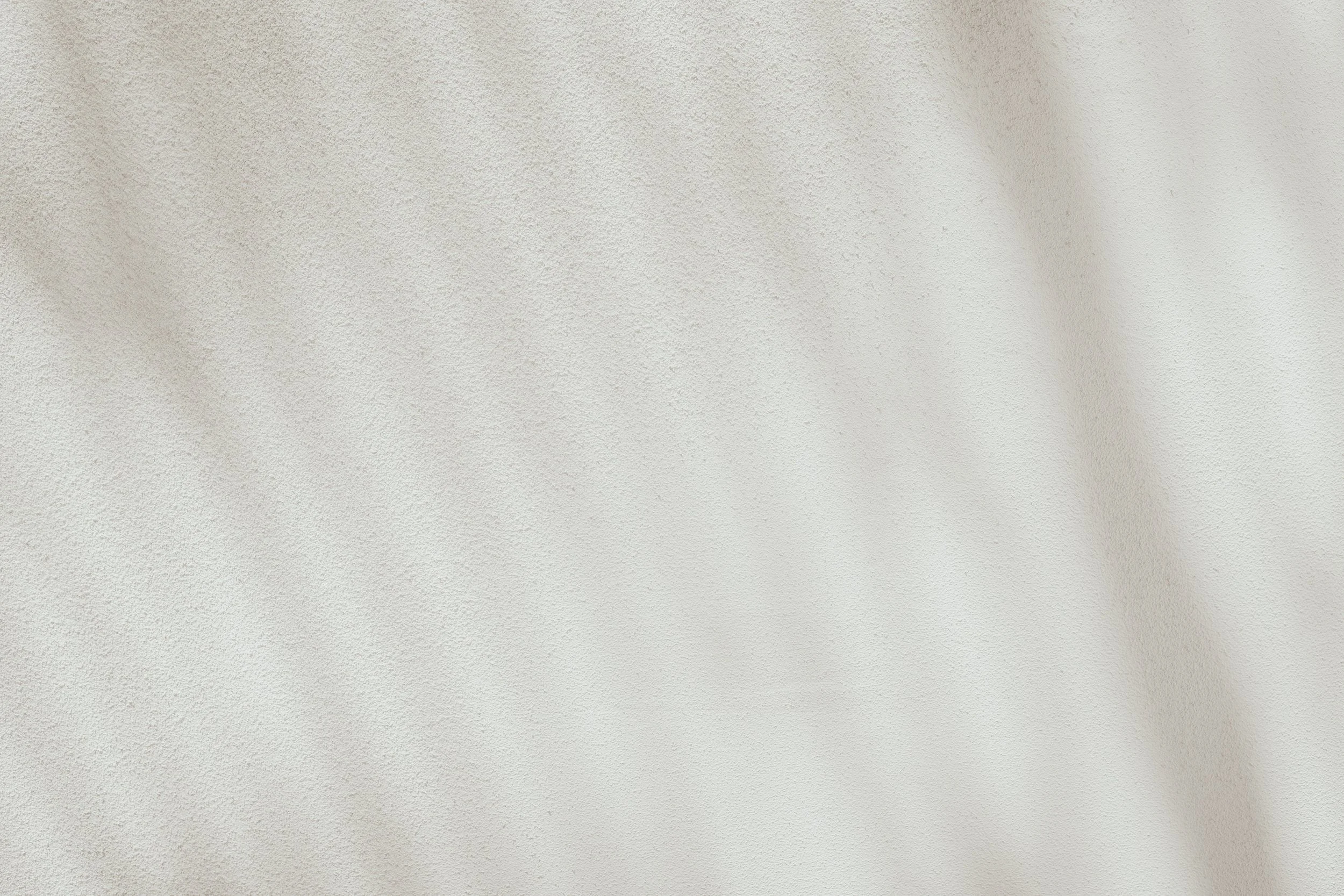 Close-up of a textured white wall and ceiling corner with shadows.