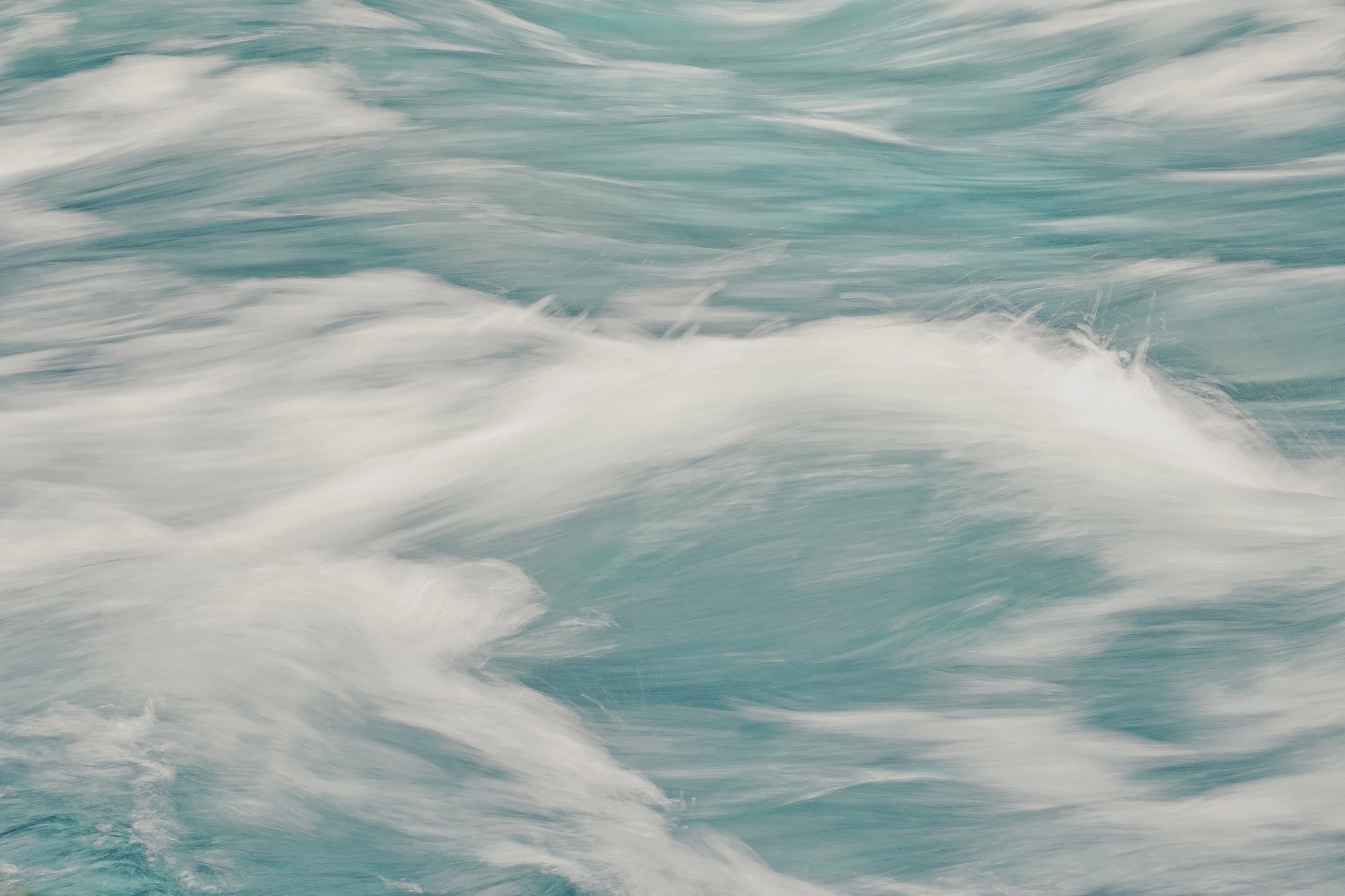 Moving ocean waves with white foam and turquoise water.
