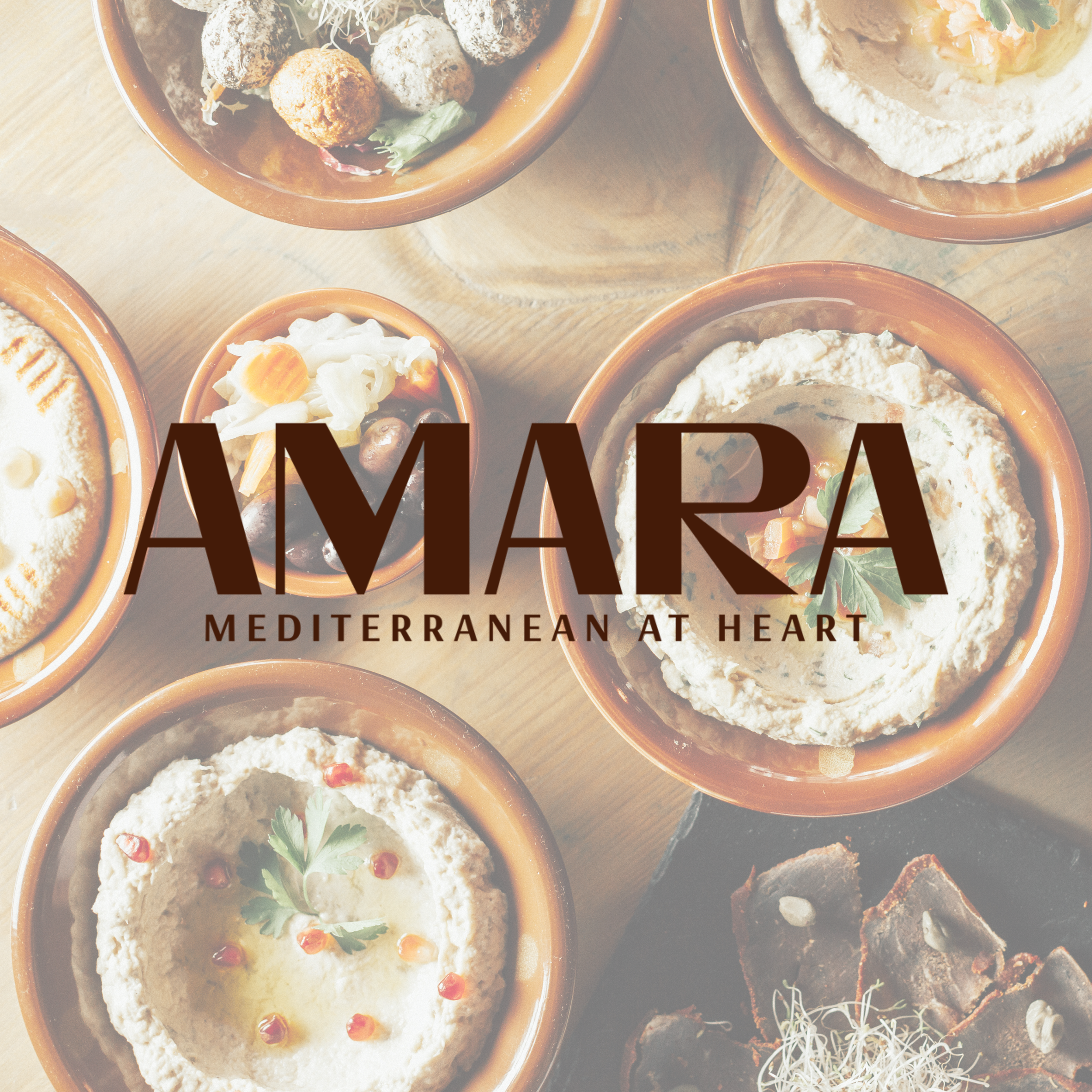 Assorted Mediterranean dishes in terracotta bowls including hummus with herbs, olives, and falafel with vegetables on a wooden table.