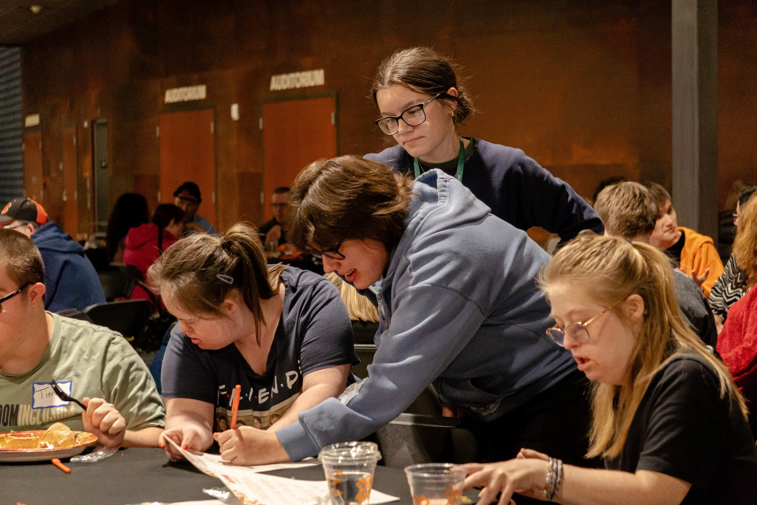 Group of young people working together at a table in a communal space.