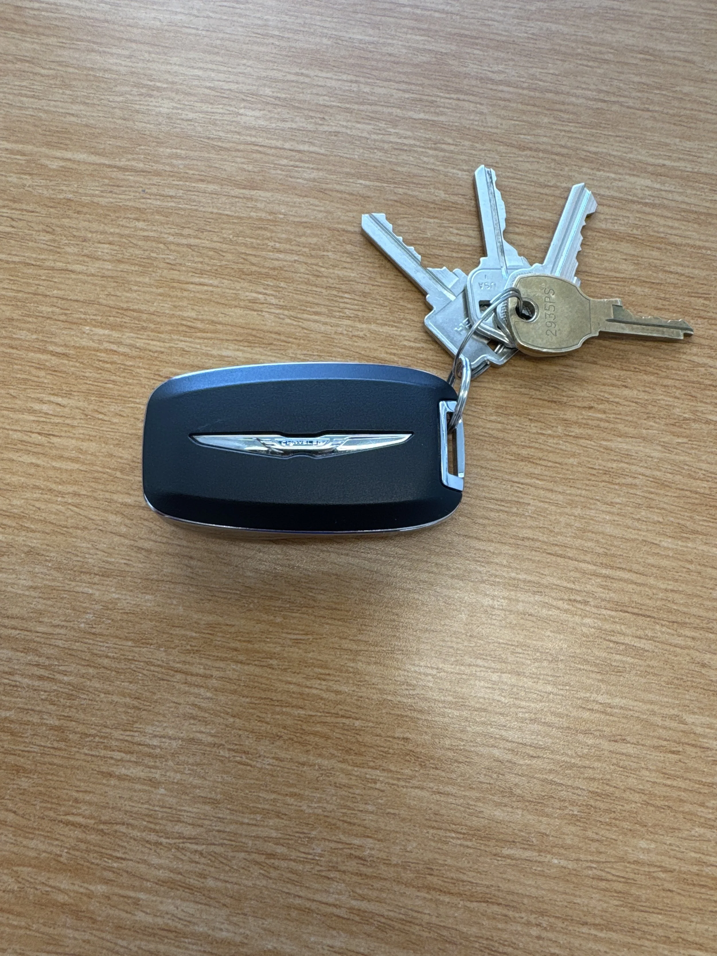 Car key fob with a set of keys attached, resting on a wooden surface.