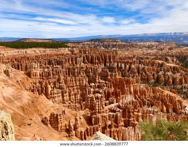 A panoramic view of colorful rock formations and hoodoos in Bryce Canyon National Park, Utah, under a partly cloudy sky.