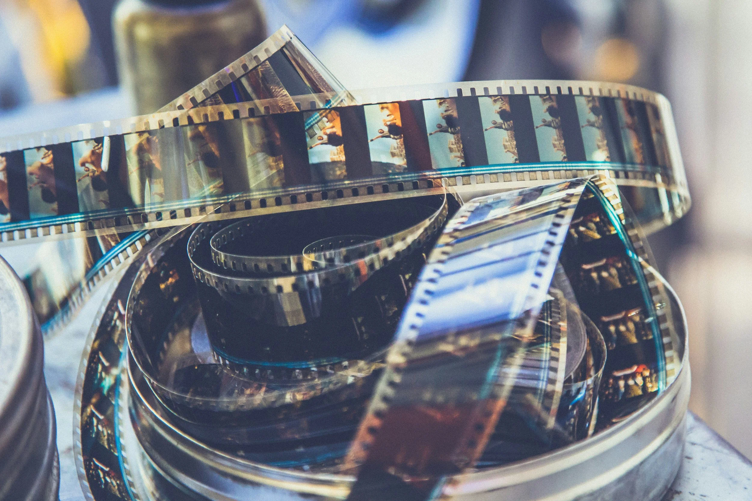 Close-up of a film strip reel inside a round metal container with multiple layers, reflecting light and displaying individual frames of a movie.