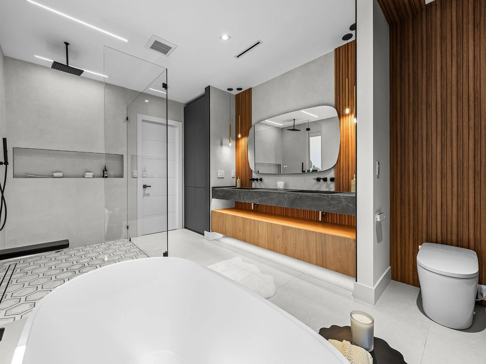 Modern bathroom with a walk-in shower, double vanity with a large mirror, wooden accents, and a toilet.