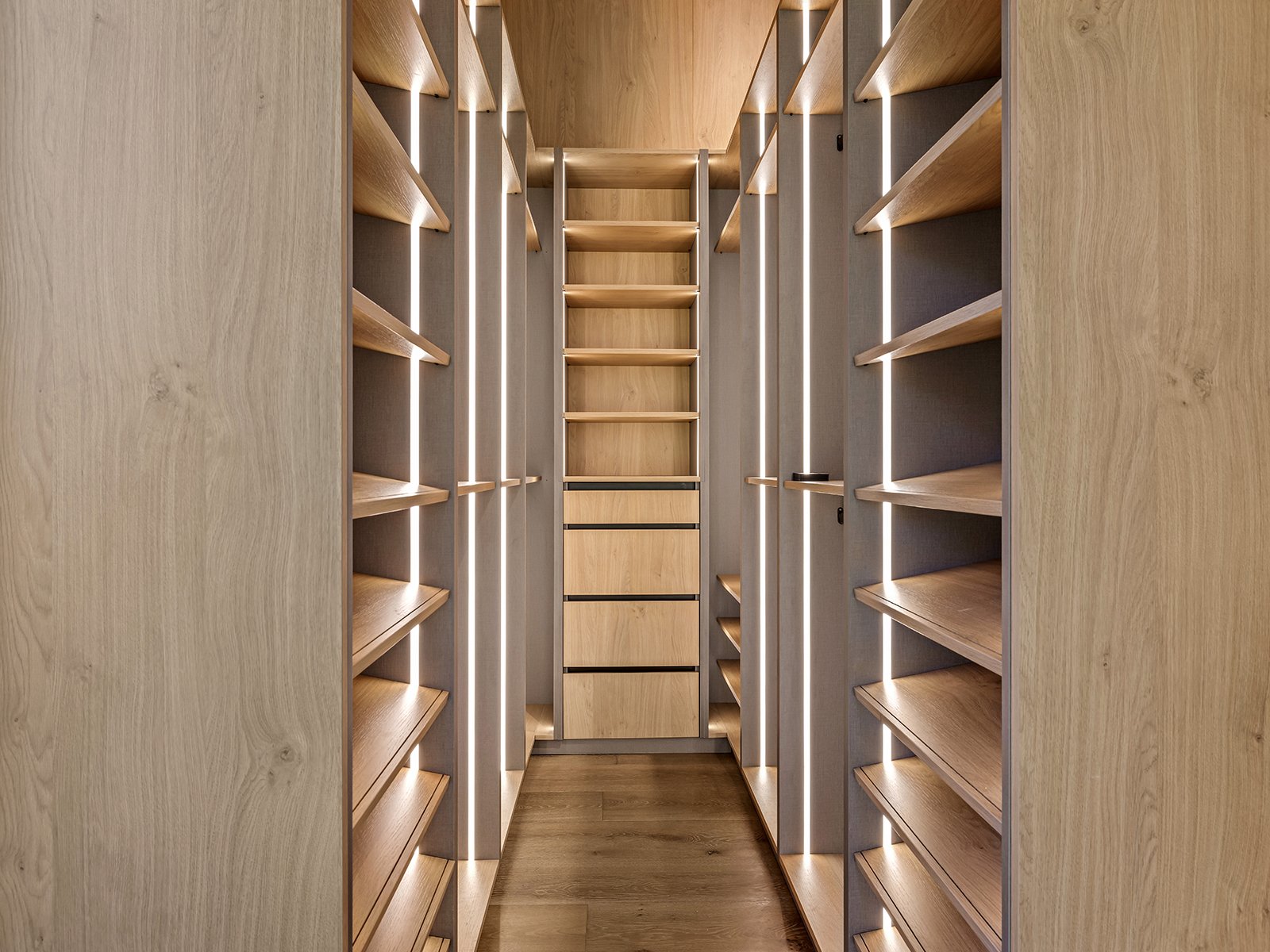 Wooden shelving units with LED lighting along the edges, forming a narrow aisle.