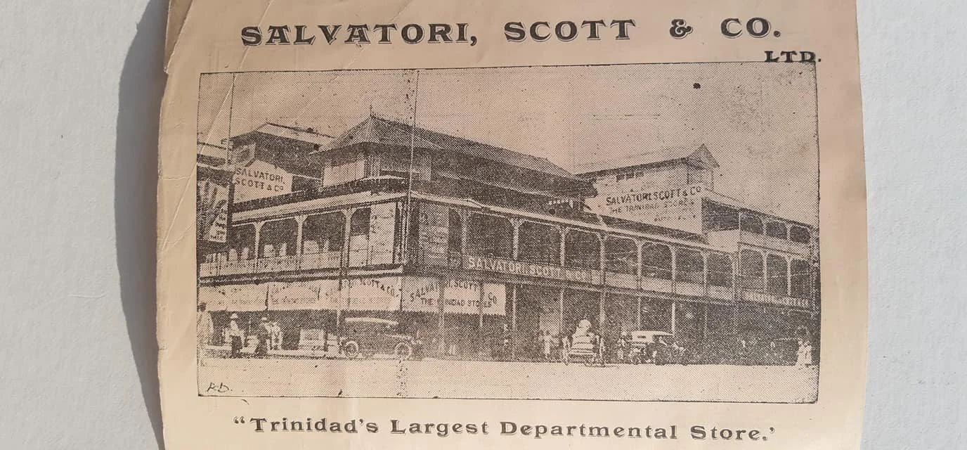 Vintage photograph of the Salvatore, Scott & Co. LTD department store building with signage and parked cars in front, described as Trinidad's largest departmental store.