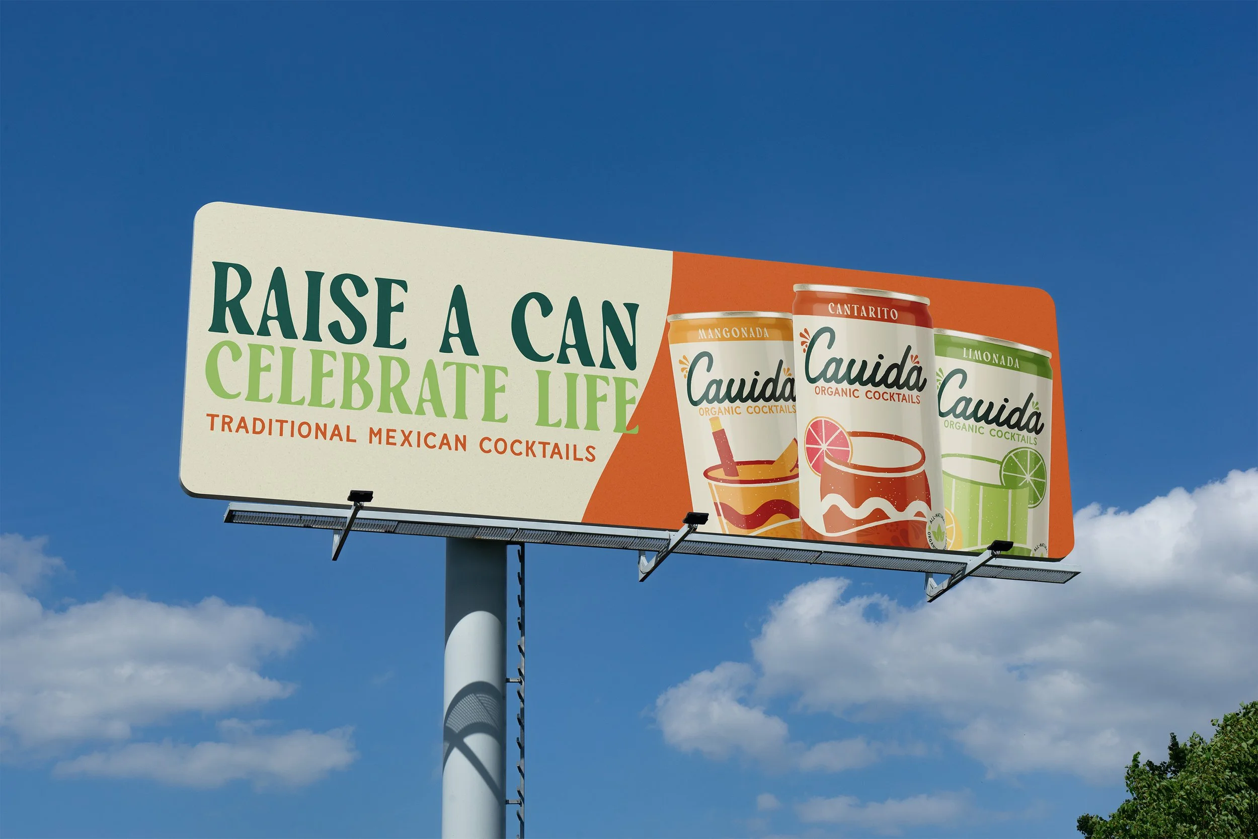 Billboard promoting traditional Mexican cocktails with the text 'Raise a Can, Celebrate Life' and images of three cans of Cauda organic cocktails in mango, cantaro, and lime flavors against a blue sky background.