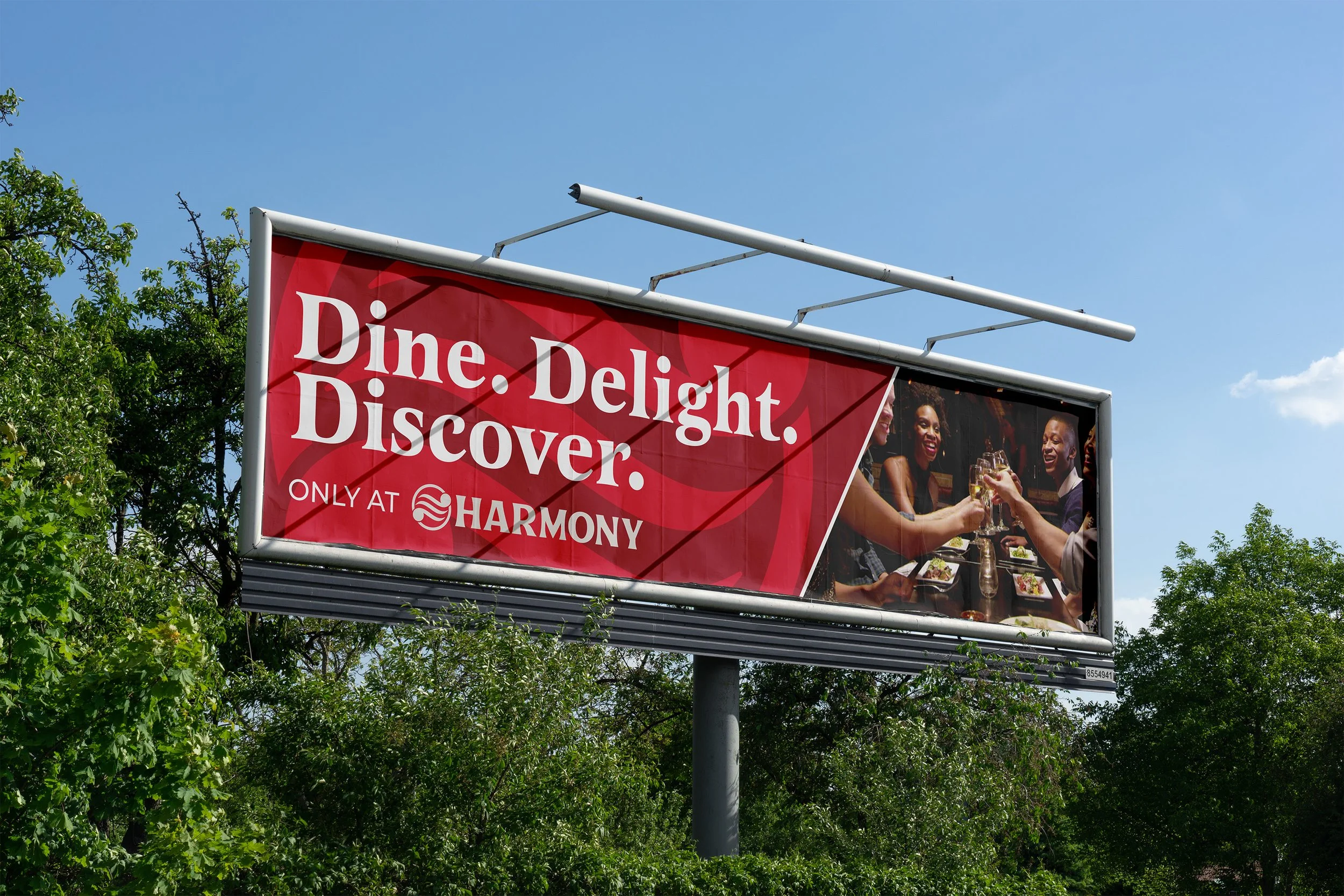 Billboard advertisement for Harmony restaurant, featuring people enjoying a meal and drinks, with the text 'Dine. Delight. Discover. Only at Harmony'
