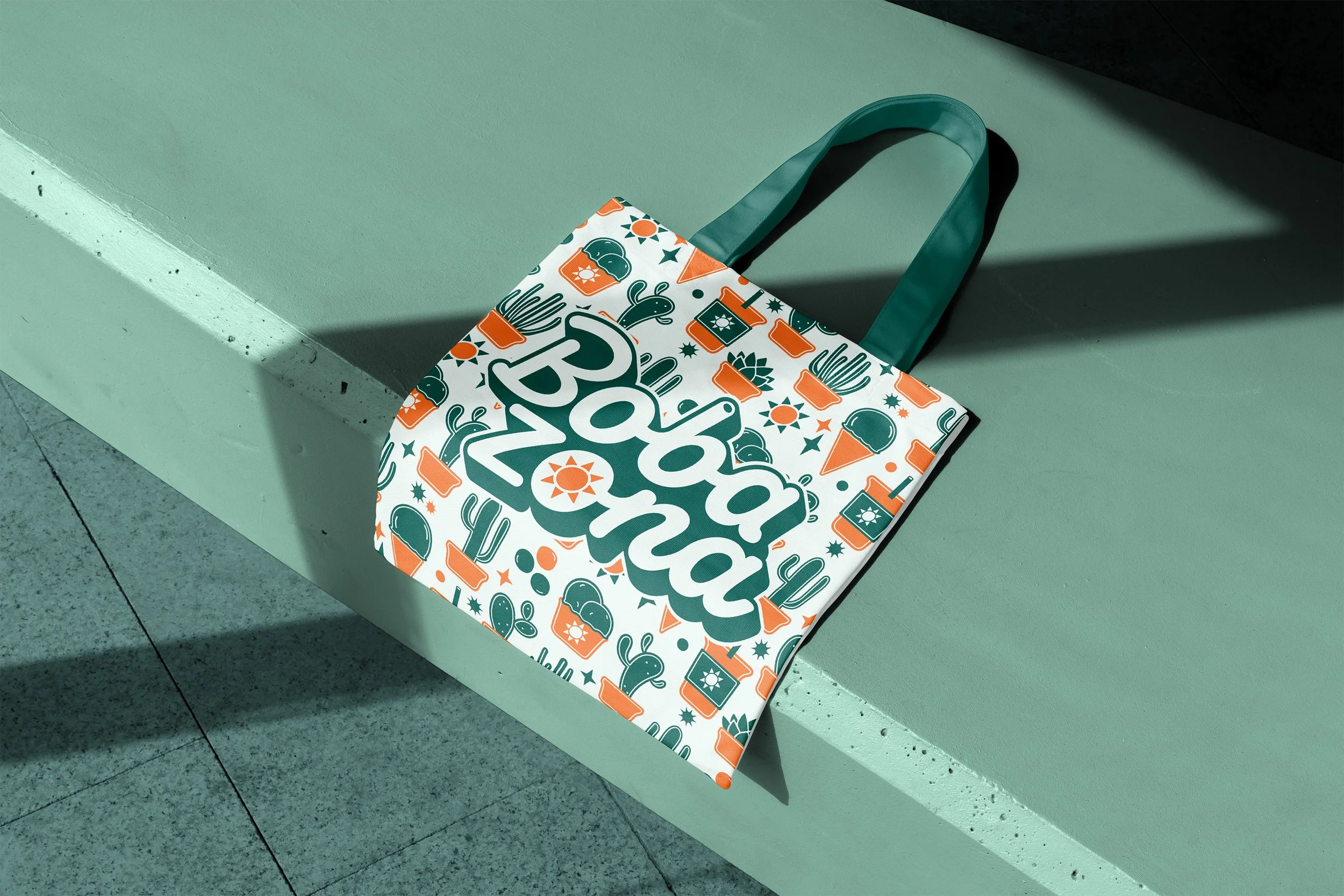 A tote bag with a Mexico theme, featuring colorful cactus, sun, and food icons, resting on a concrete ledge with sunlight casting shadows.